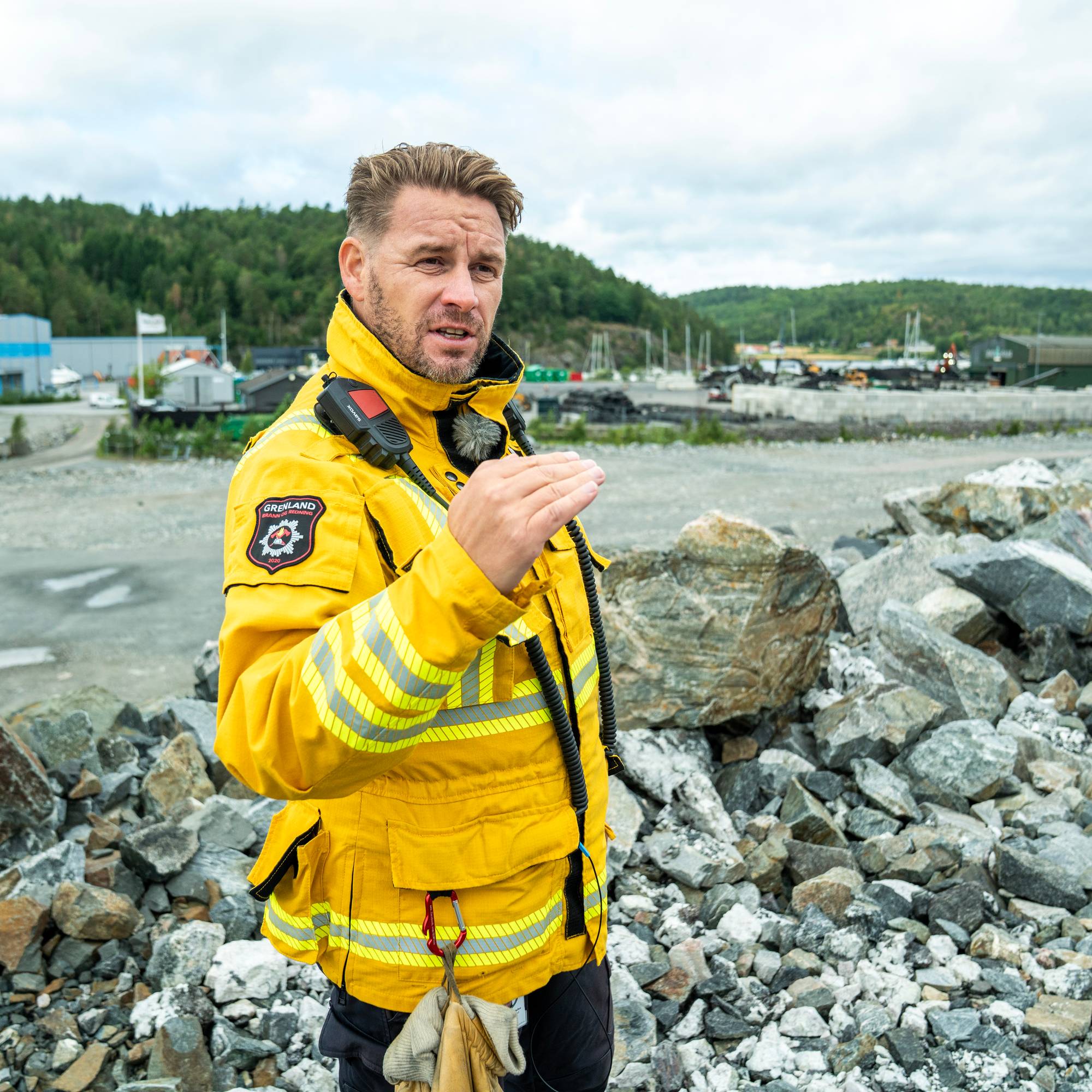 en mann i gul jakke som står på steiner ved vann