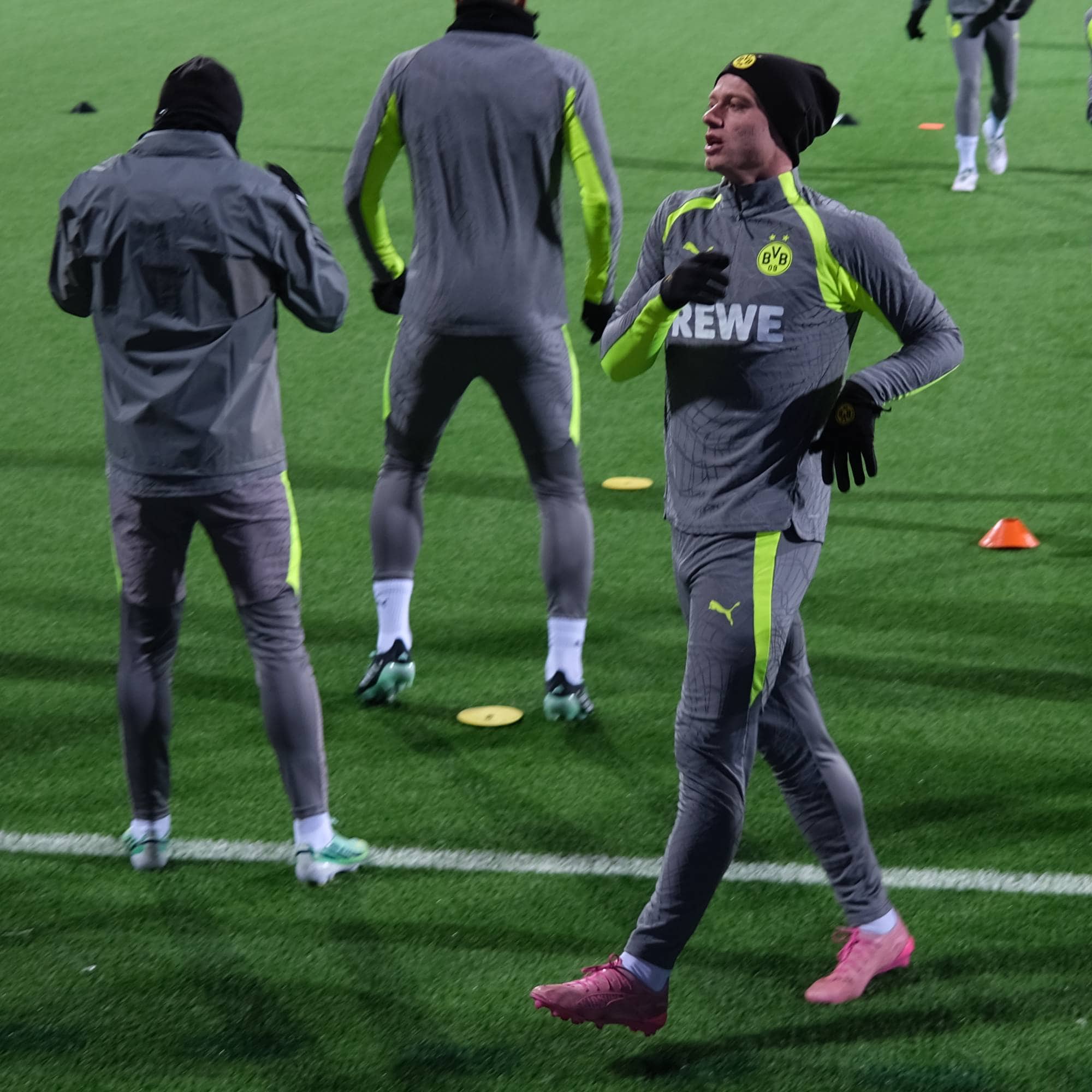 Fotballspillere i Borussia Dortmund-treningstøy trener på en gressbane. (Bildebeskrivelsen er laget av en KI-tjeneste)