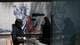 Reuters To personer går forbi en anti-amerikansk vegg plakat i teheran