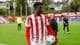 Foto: Rune Stoltz Bertinussen / NTB En fotballspiller i rød- og hvite drakt holder en fotball. Han er på en grønn gressbane med tribuner i bakgrunnen. Flere personer sees i bakgrunnen. (Bildebeskrivelsen er laget av en KI-tjeneste)