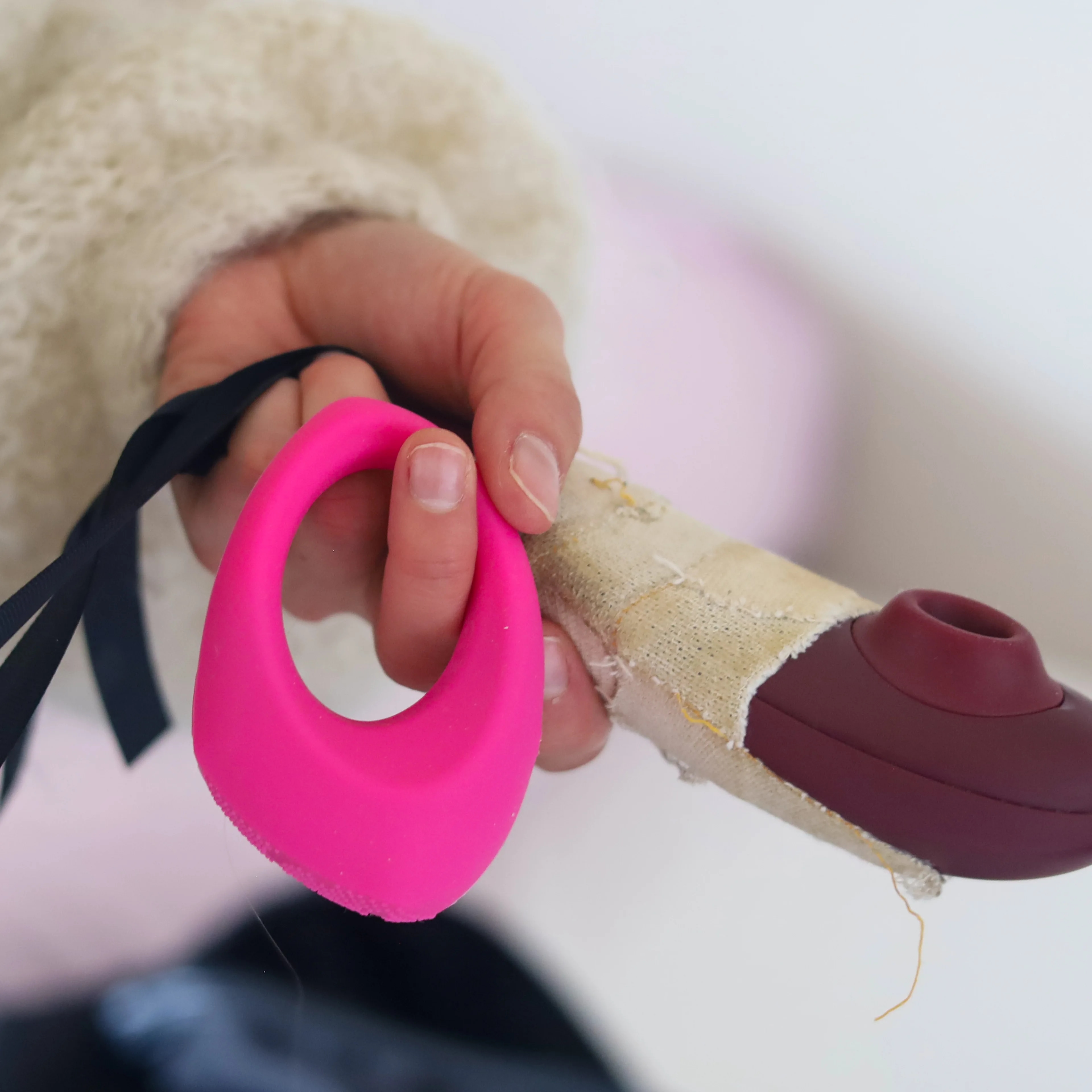 En hånd holder en rosa ring og en lilla vibrator.