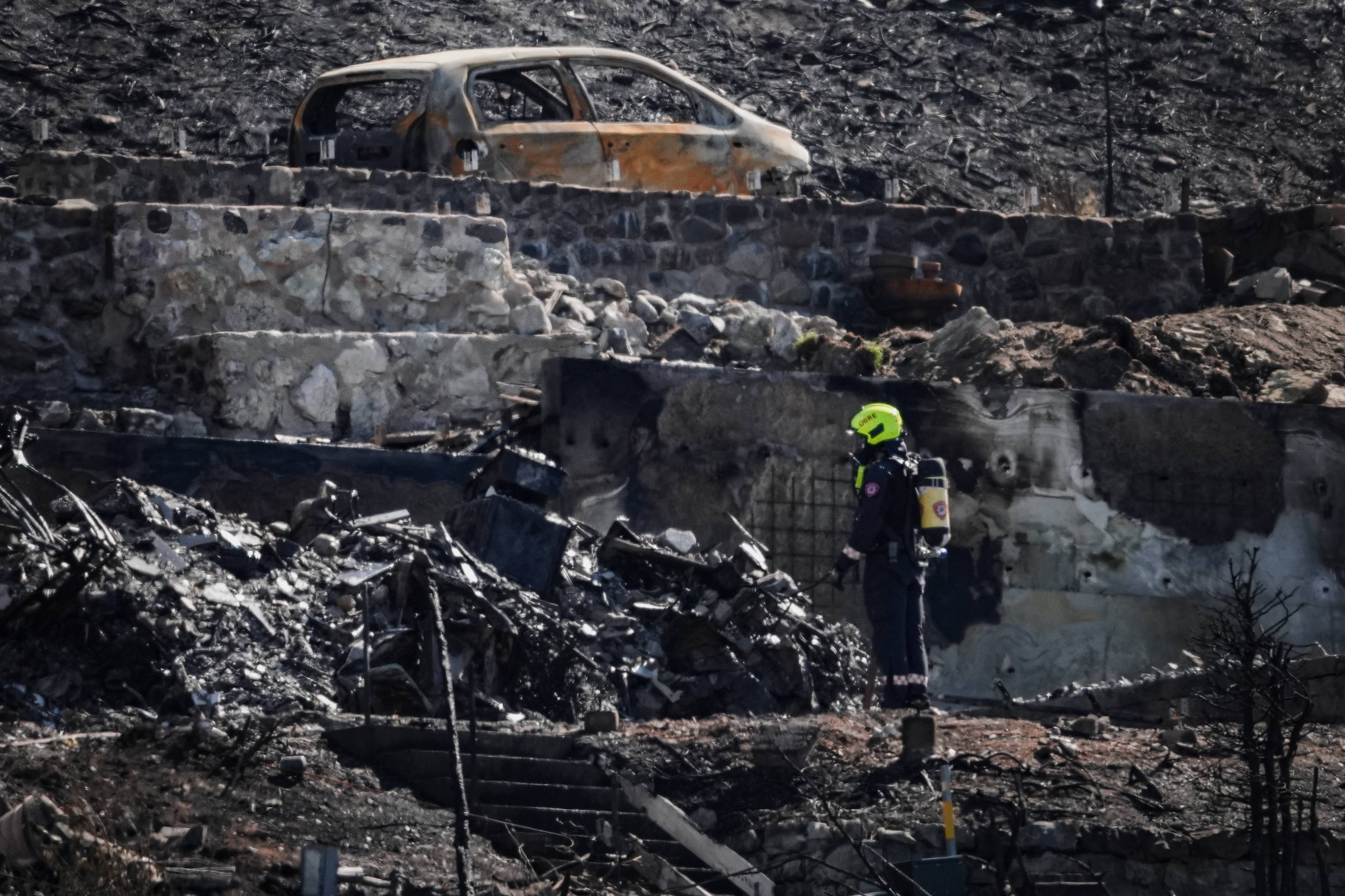 En røykdykker står i ruinene av et nedbrent nabolag