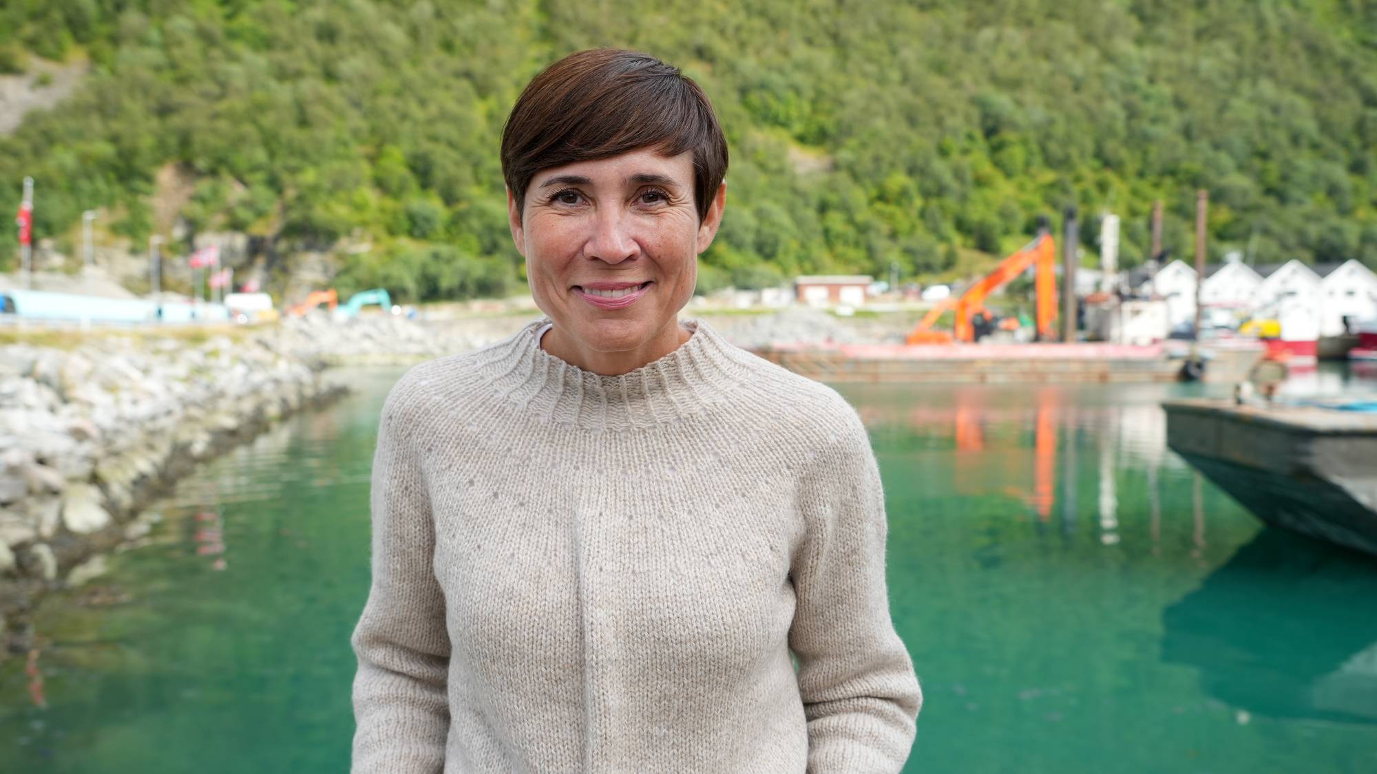 Høyre-leder Ine Eriksen Søreide foran en småbåthavn med anleggsmaskiner i bakgrunnen. (Bildebeskrivelsen er laget av en KI-tjeneste)