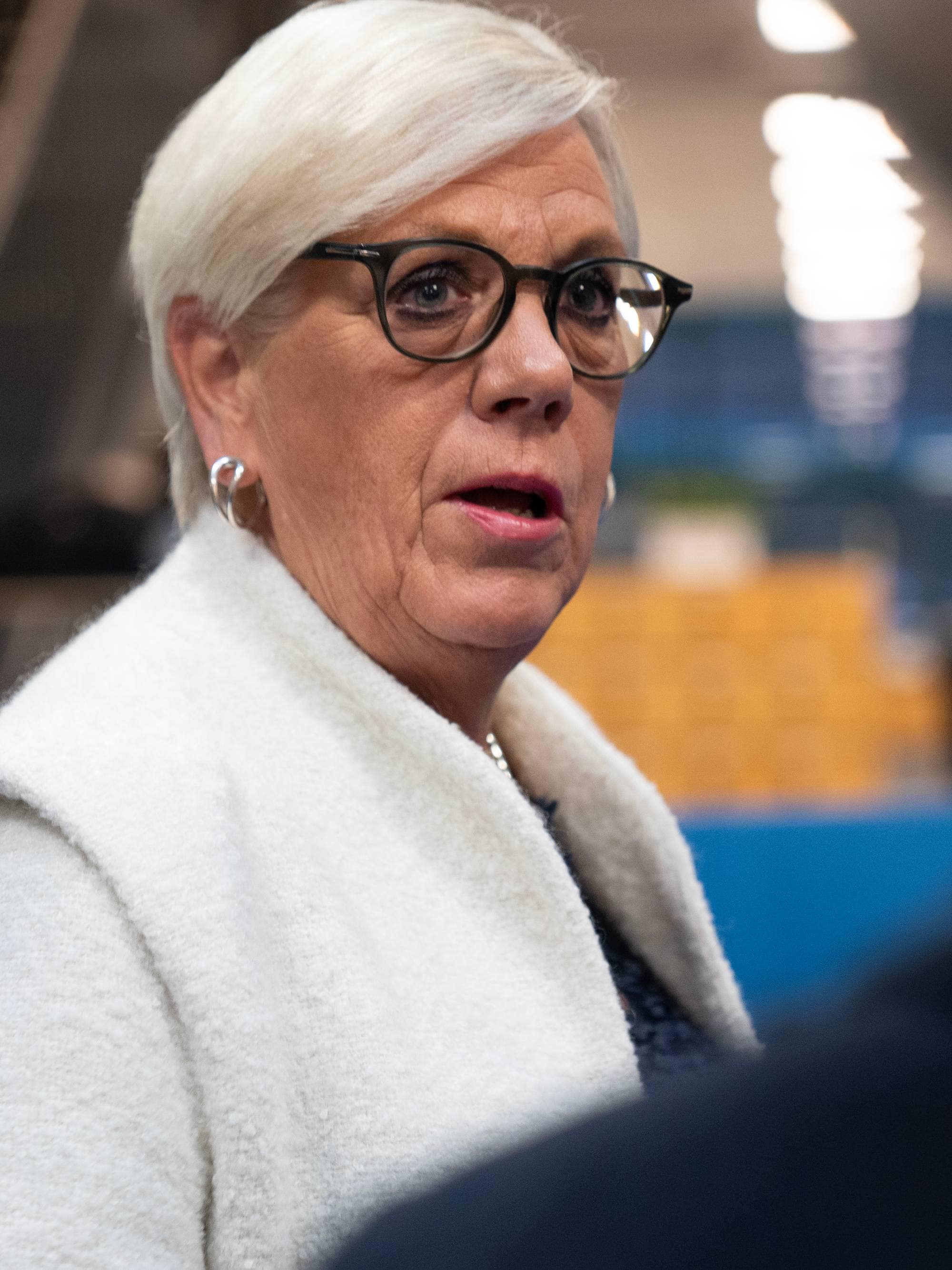 Hilde Henriksen Waage med briller i samtale med en person sett bakfra. (Bildebeskrivelsen er laget av en KI-tjeneste)