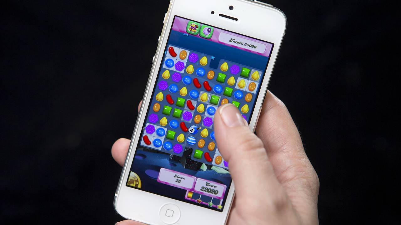 Nærbilde av en mobil med Candy crush, holdt av en kvinnehånd