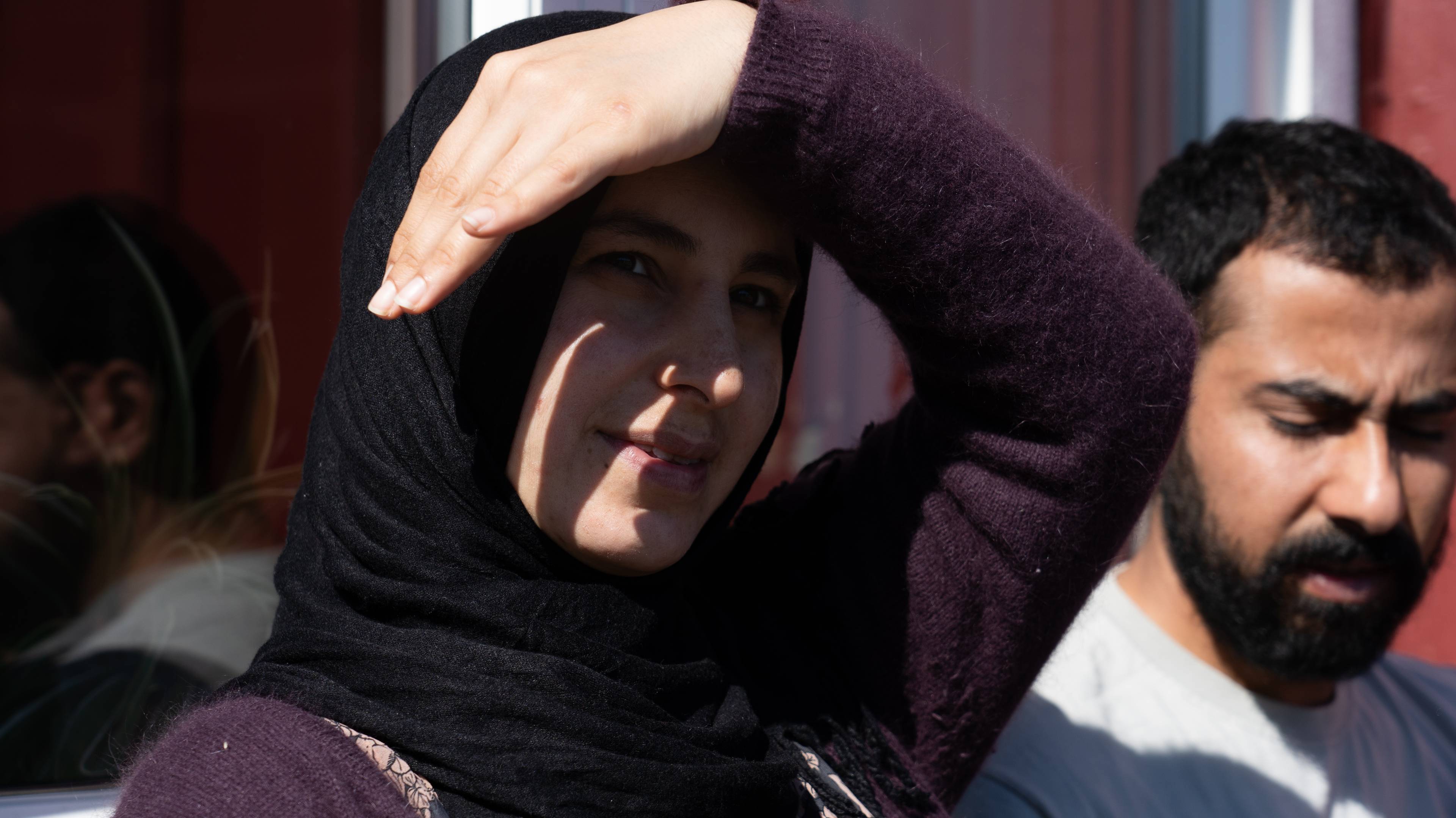 En kvinne med hijab holder hånden over pannen. En mann med skjegg står ved siden av henne. Begge ser ut til å være ute. Bakgrunnen er utydelig. (Bildebeskrivelsen er laget av en KI-tjeneste)