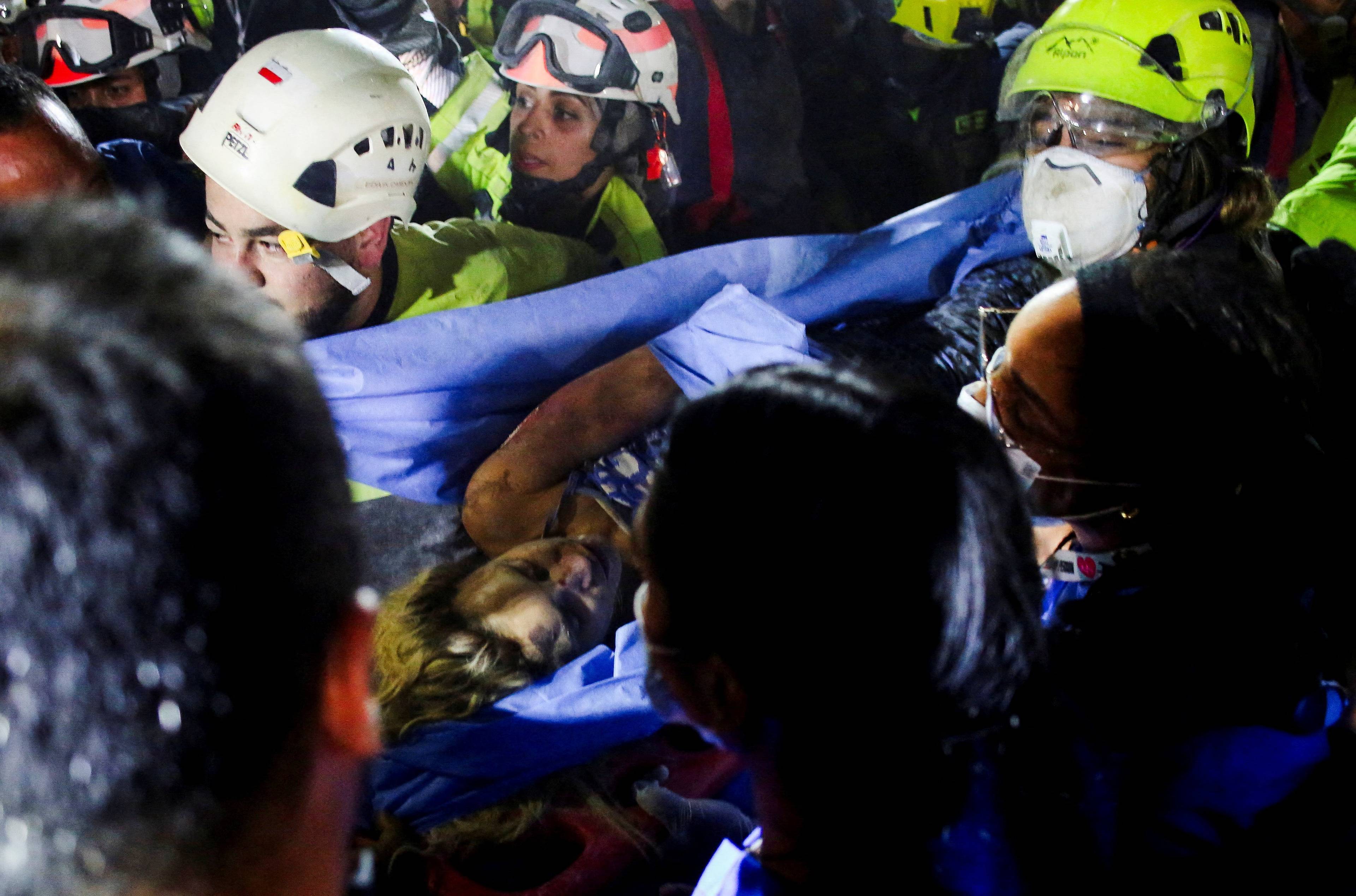 Redningsmannskaper med hjelm og maske bærer en person på en båre. (Bildebeskrivelsen er laget av en KI-tjeneste)