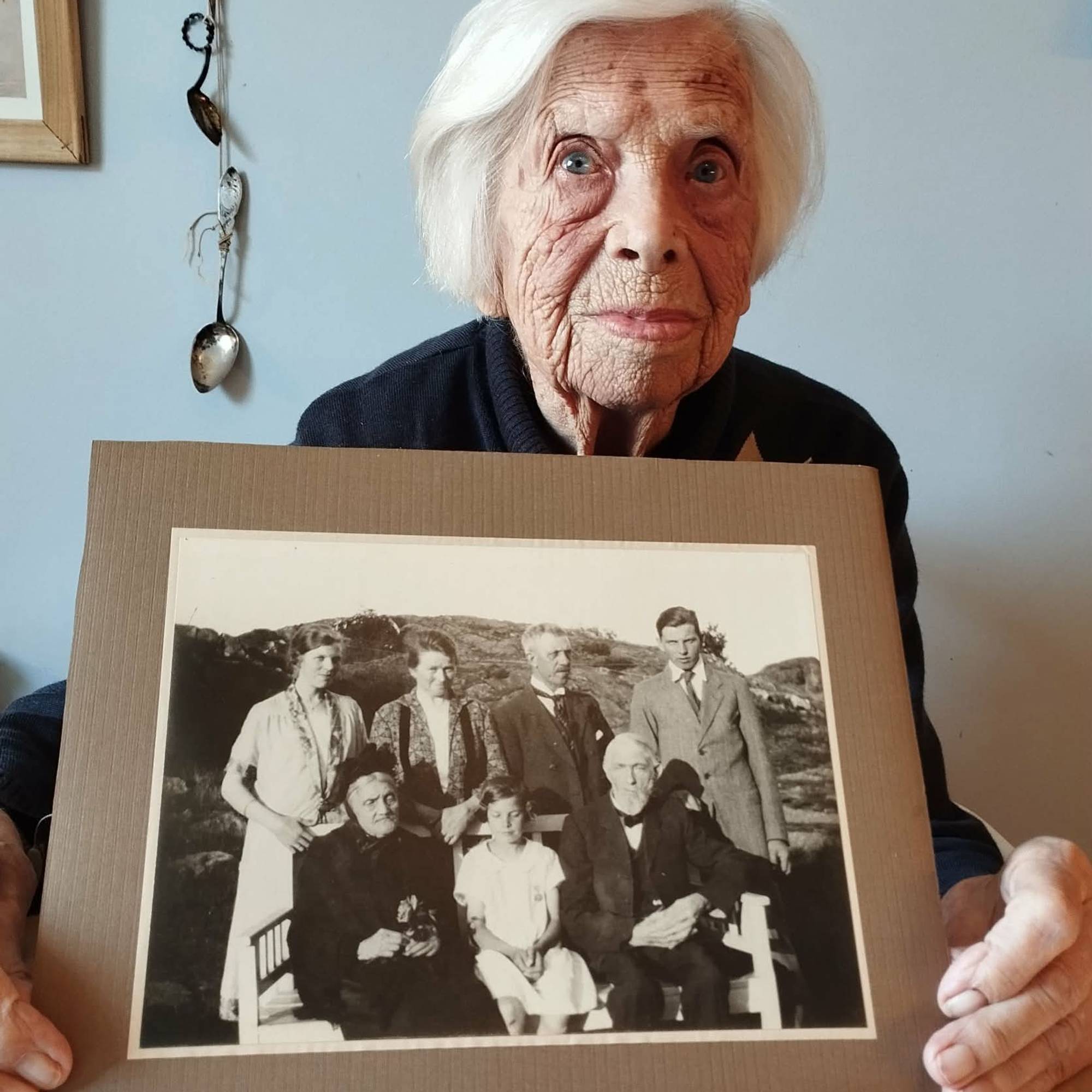 Eldre kvinne med foto i hendene.