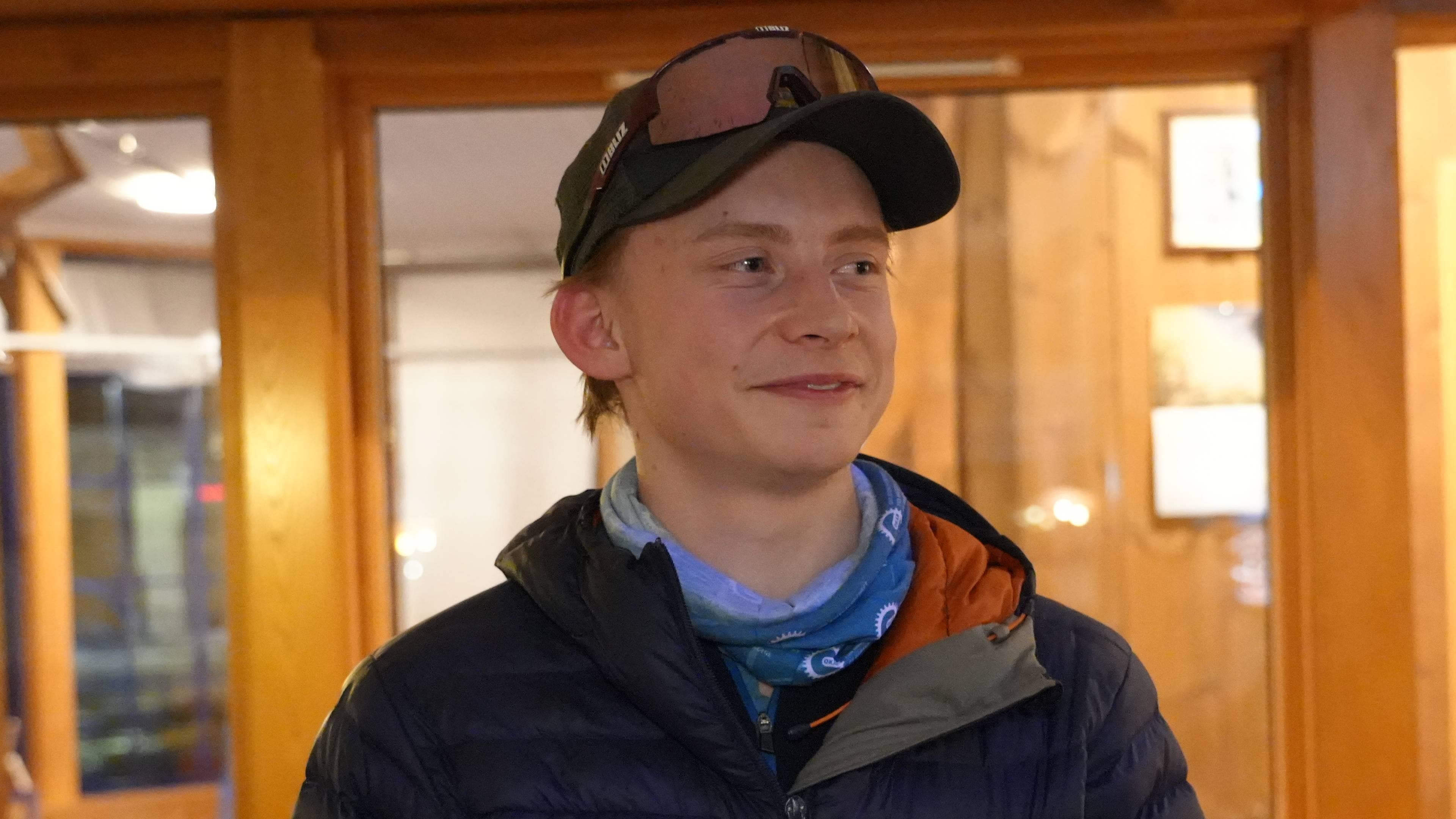 en person som står, i blå jakke og caps.