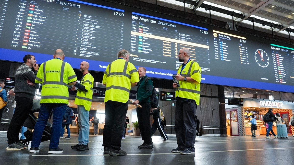 Streikevakter i gule vester står foran en tavle med kansellerte togavganger på Oslo S. (Bildebeskrivelsen er laget av en KI-tjeneste) FOTO: Terje Pedersen/NTB