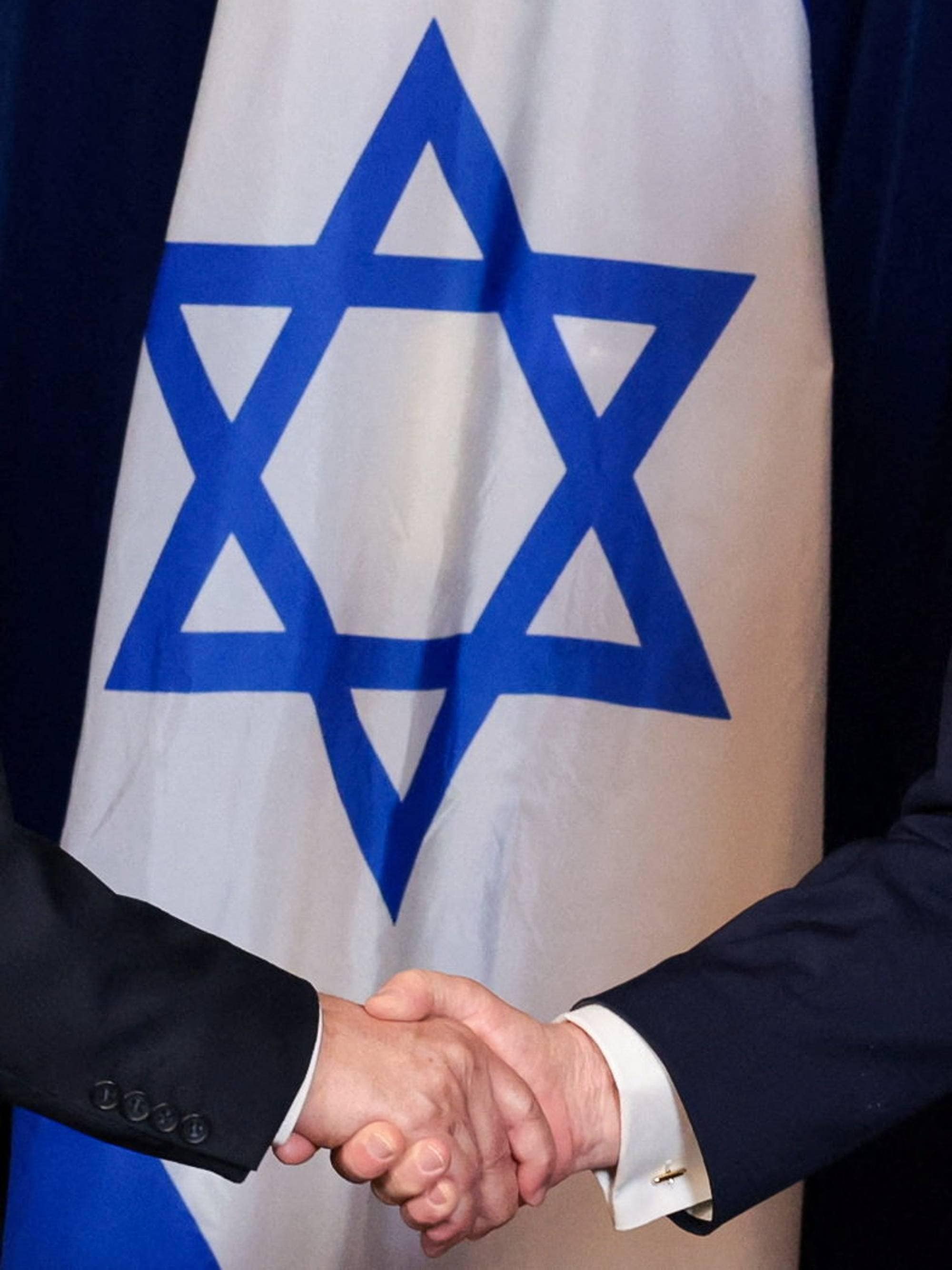 Et håndtrykk mellom to menn. I bakgrunnen davidstjerna på det israelske flagget.