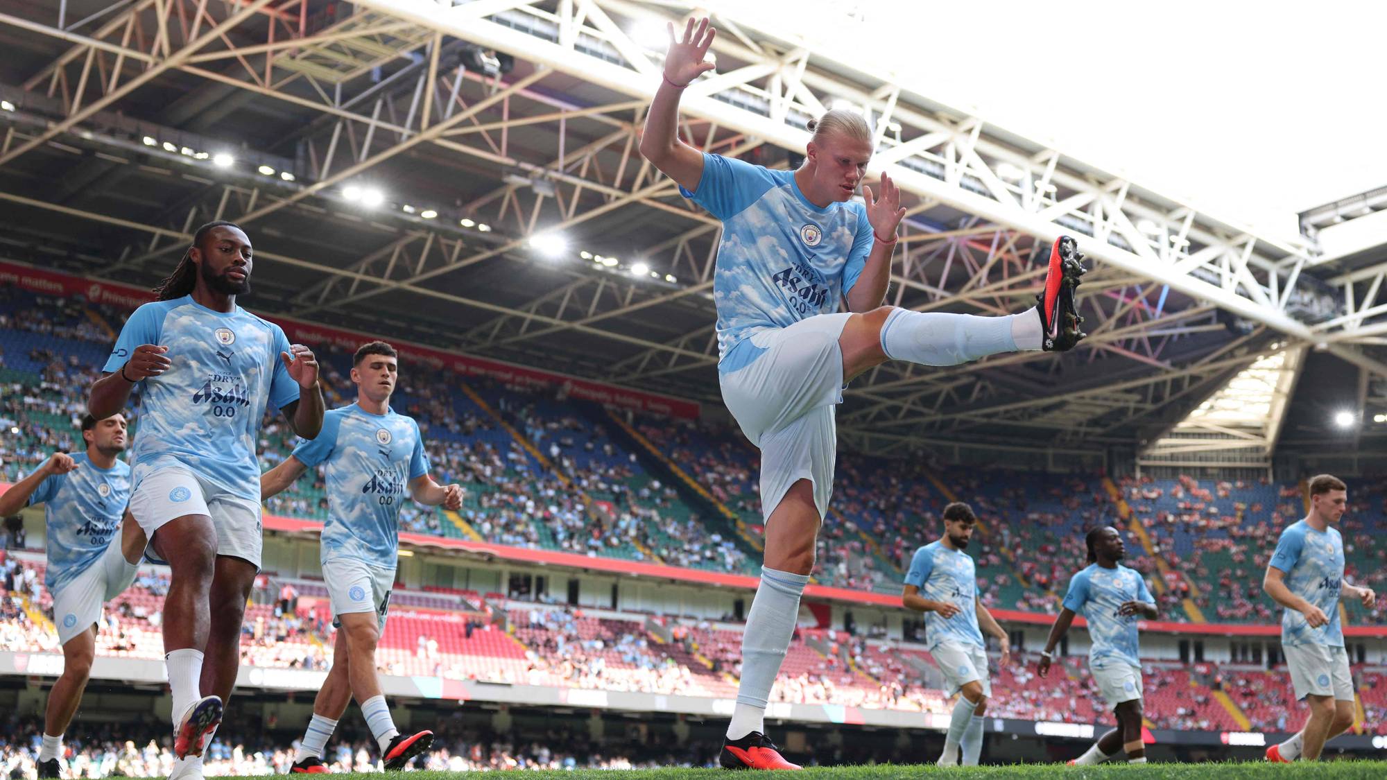 Erling Braut Haaland utfører en sparkøvelse foran lagkamerater på fotballbanen på Etihad Stadium. (Bildebeskrivelsen er laget av en KI-tjeneste)