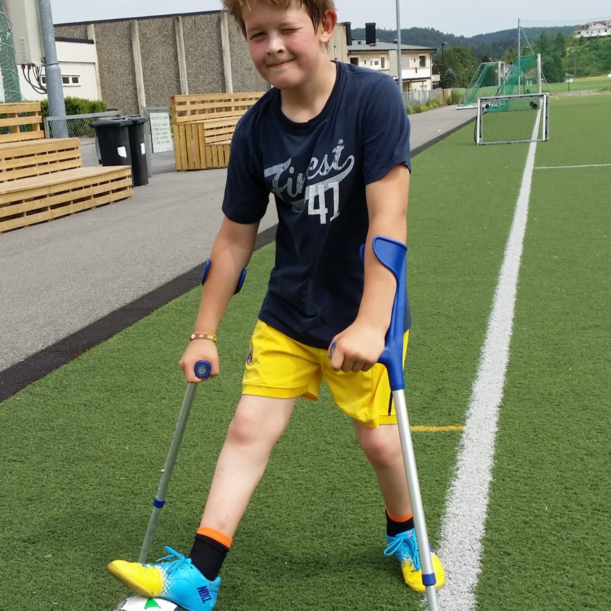 En liten gutt spiller fotball med krykker.