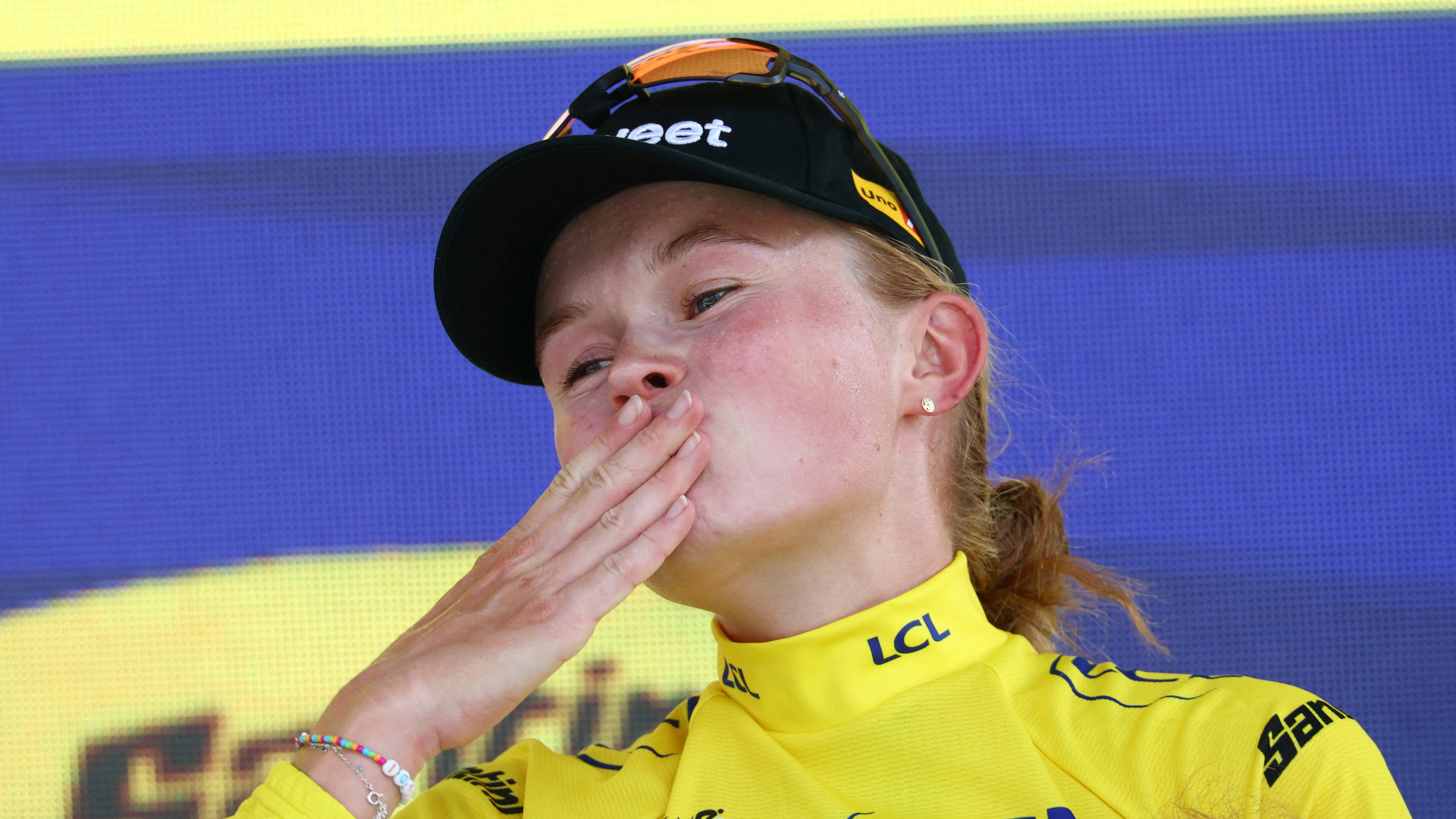 Syklist sender et kyss til publikum mens hun bærer gul ledertrøye fra Tour de France. (Bildebeskrivelsen er laget av en KI-tjeneste)