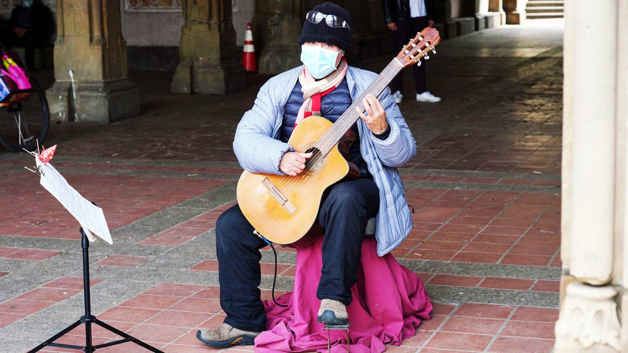 En gatemusikant med munnbind i Cenntral Park i New York lørdag.