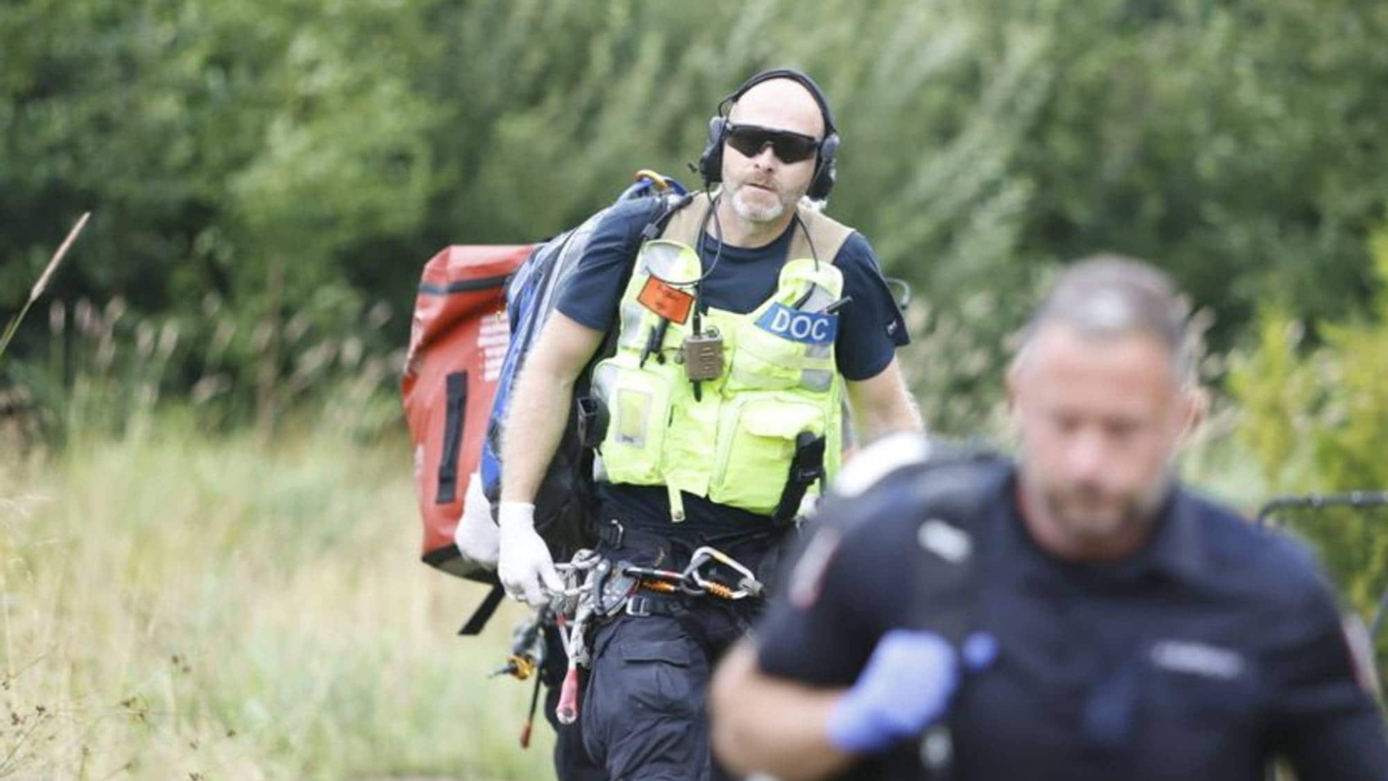 To personer fra redningsselskapet går i en skog.