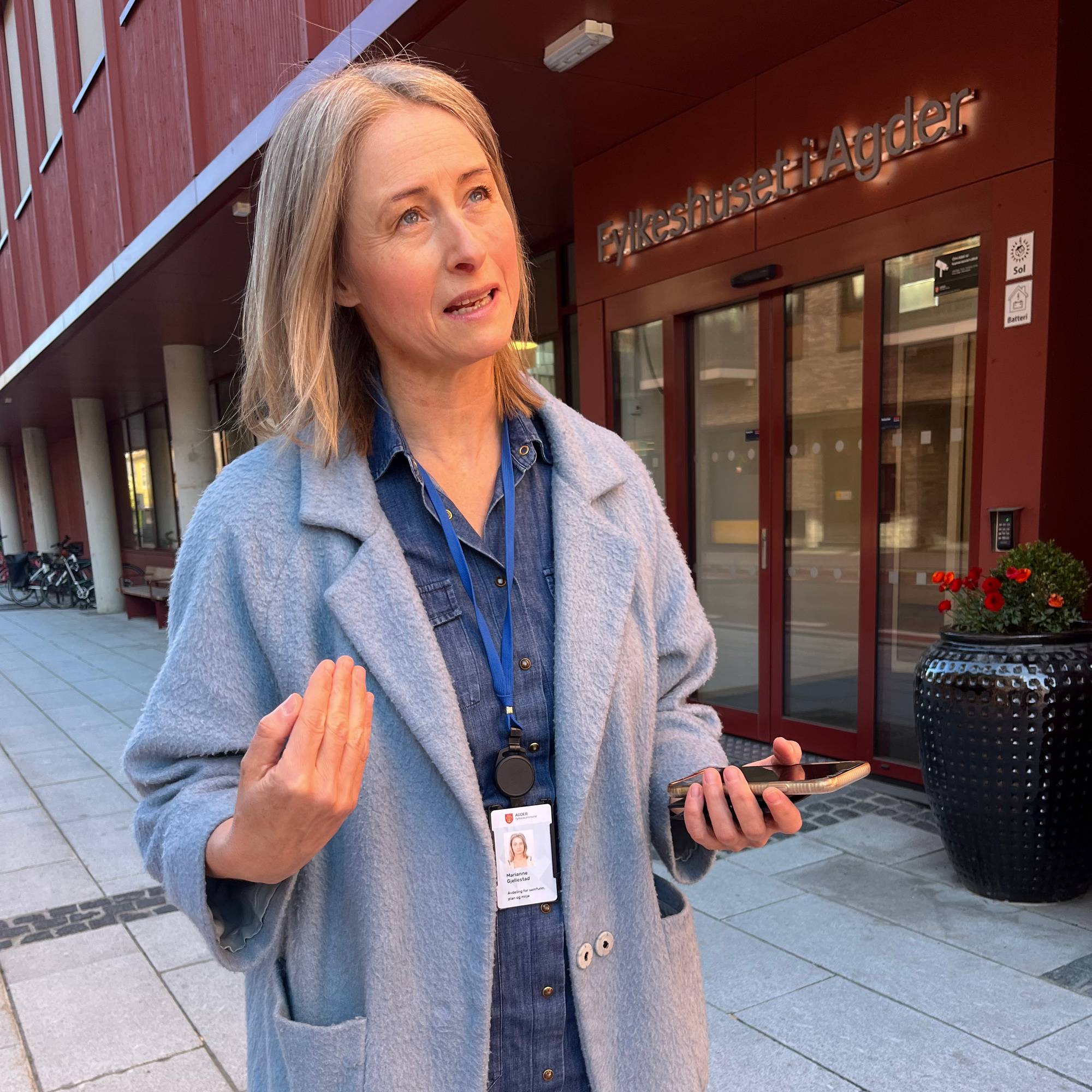 Kvinne i blå jakke utenfor et bygg. 
