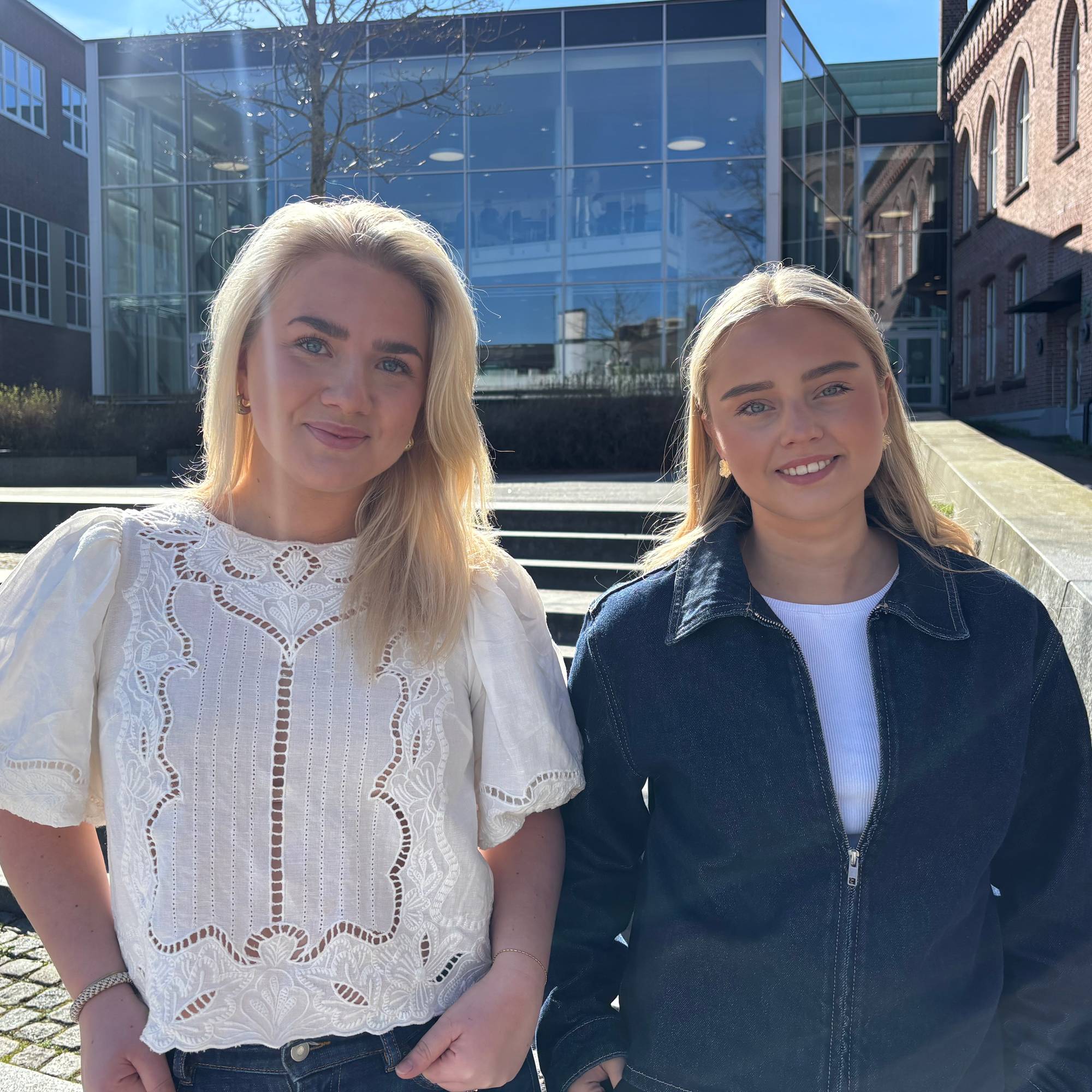 Kvinne i blå jakke og kvinne i hvit topp i sol