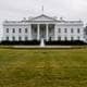 Julia Demaree Nikhinson / AP / NTB Det vises et bilde av Det hvite hus, en stor, hvit bygning med søyler og flere vinduer. I forgrunnen er det en stor, grønn gressplen som er godt vedlikeholdt. Det er trær på begge sider av bygningen, og en fontene er synlig foran. Himlen er grå og overskyet, noe som gir en dyster atmosfære. (Bildebeskrivelsen er laget av en KI-tjeneste)