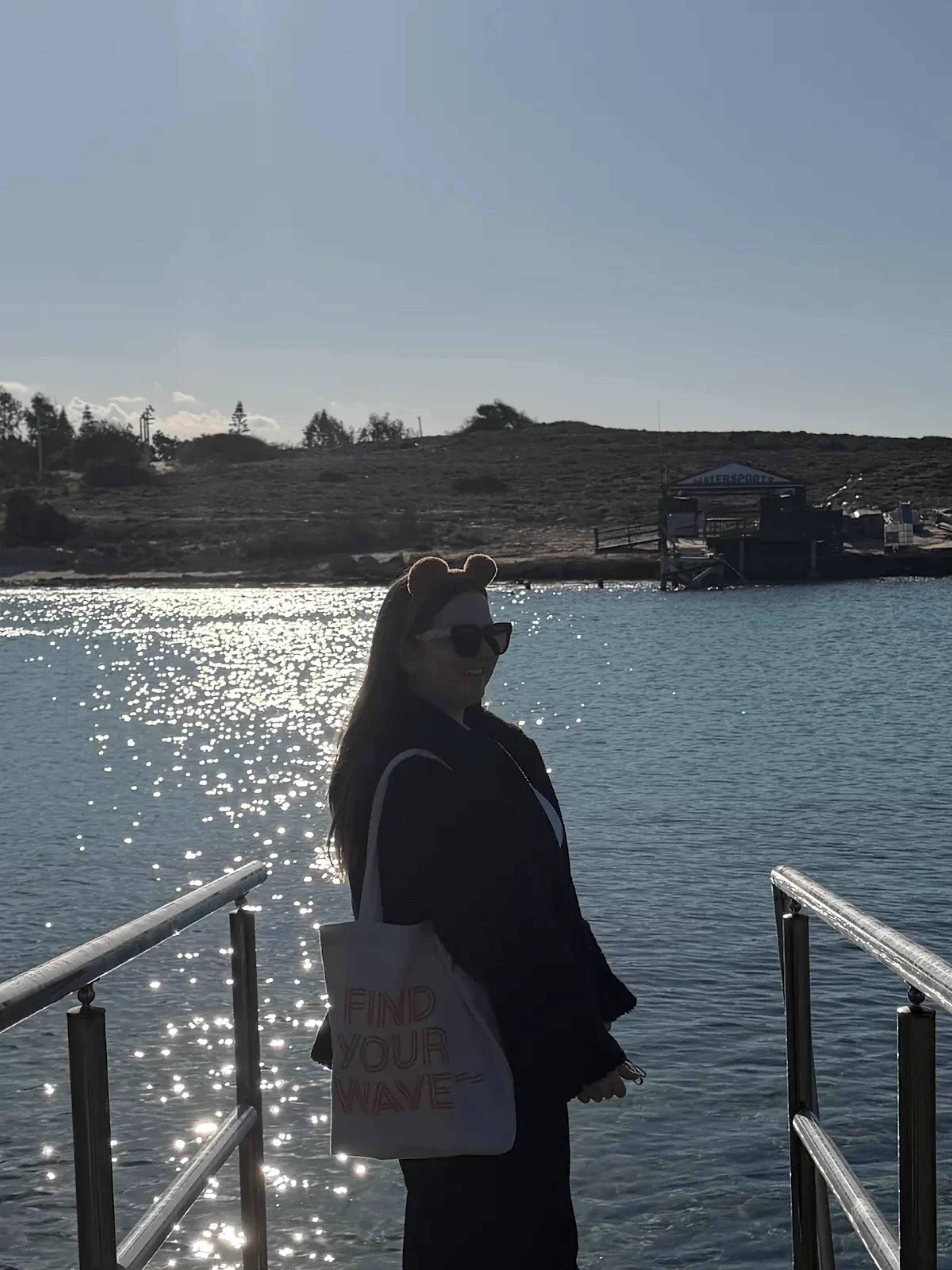 Ei jente med langt hår, hun har solbriller på og bjørneører på hodet