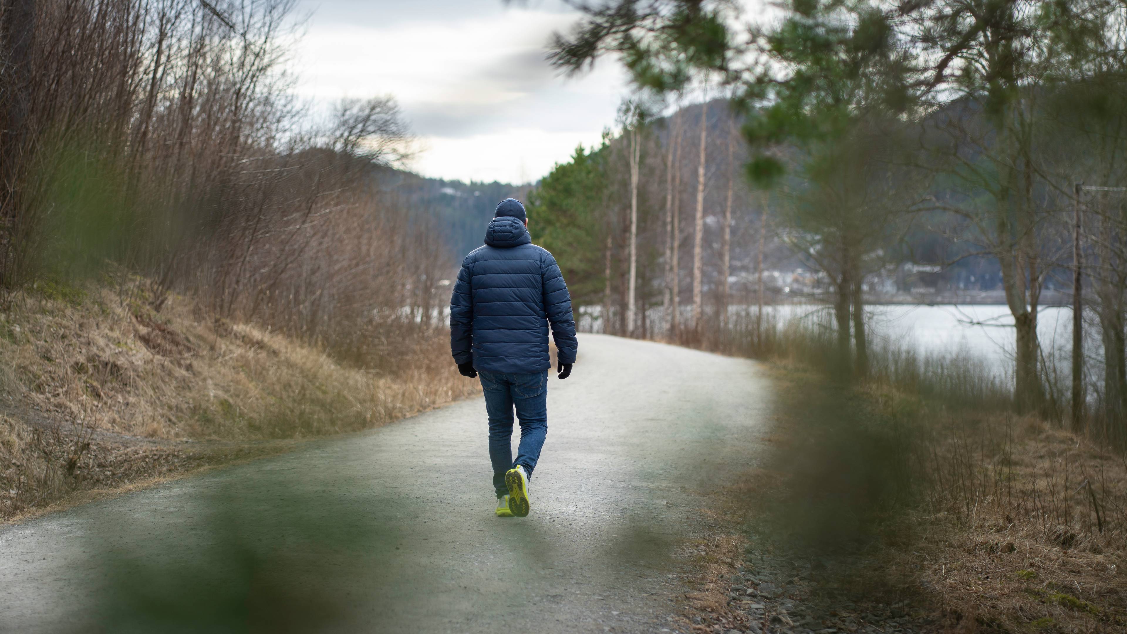 Mann i helfigur med ryggen til går langs sti