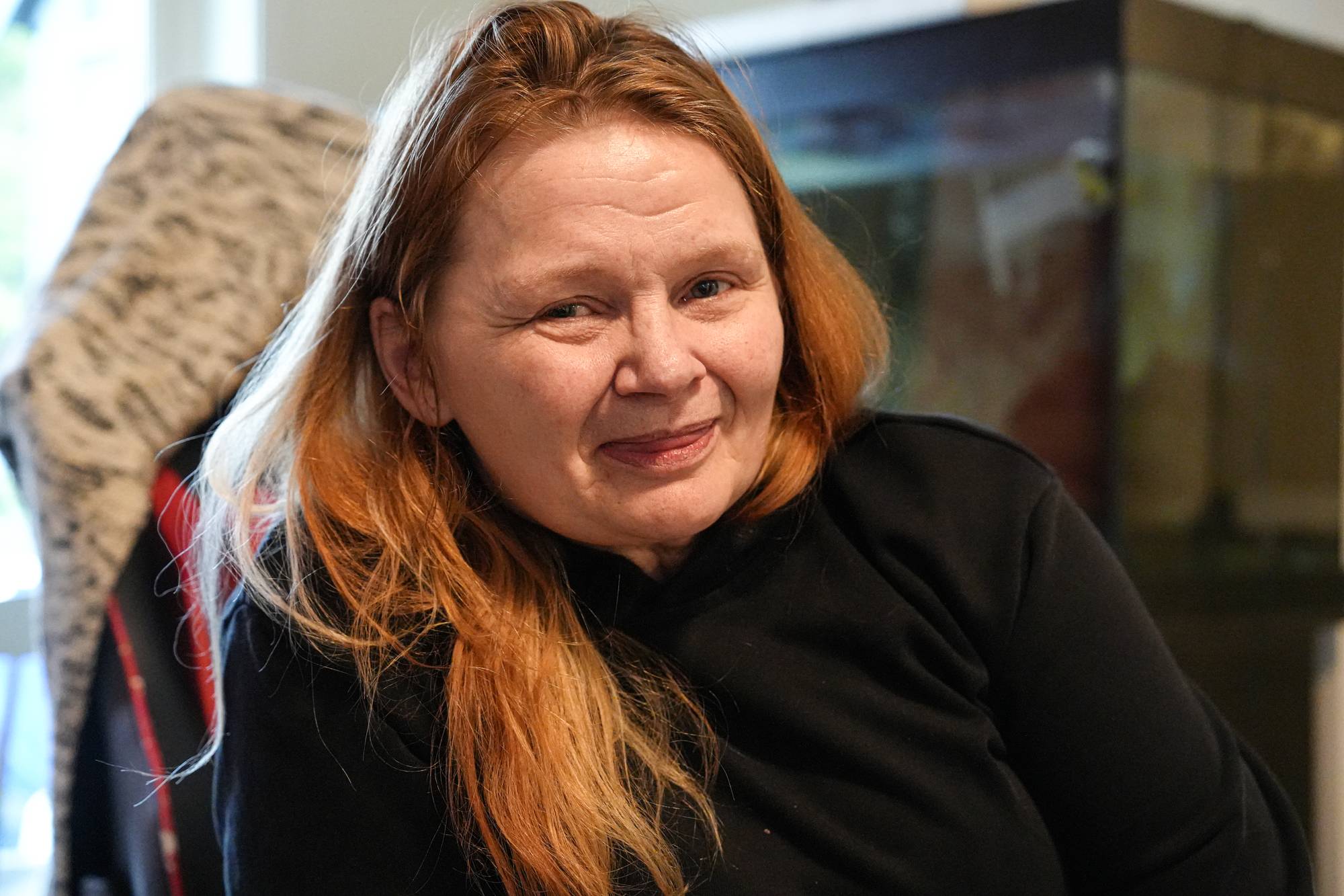 En kvinne med langt, rødt hår smiler