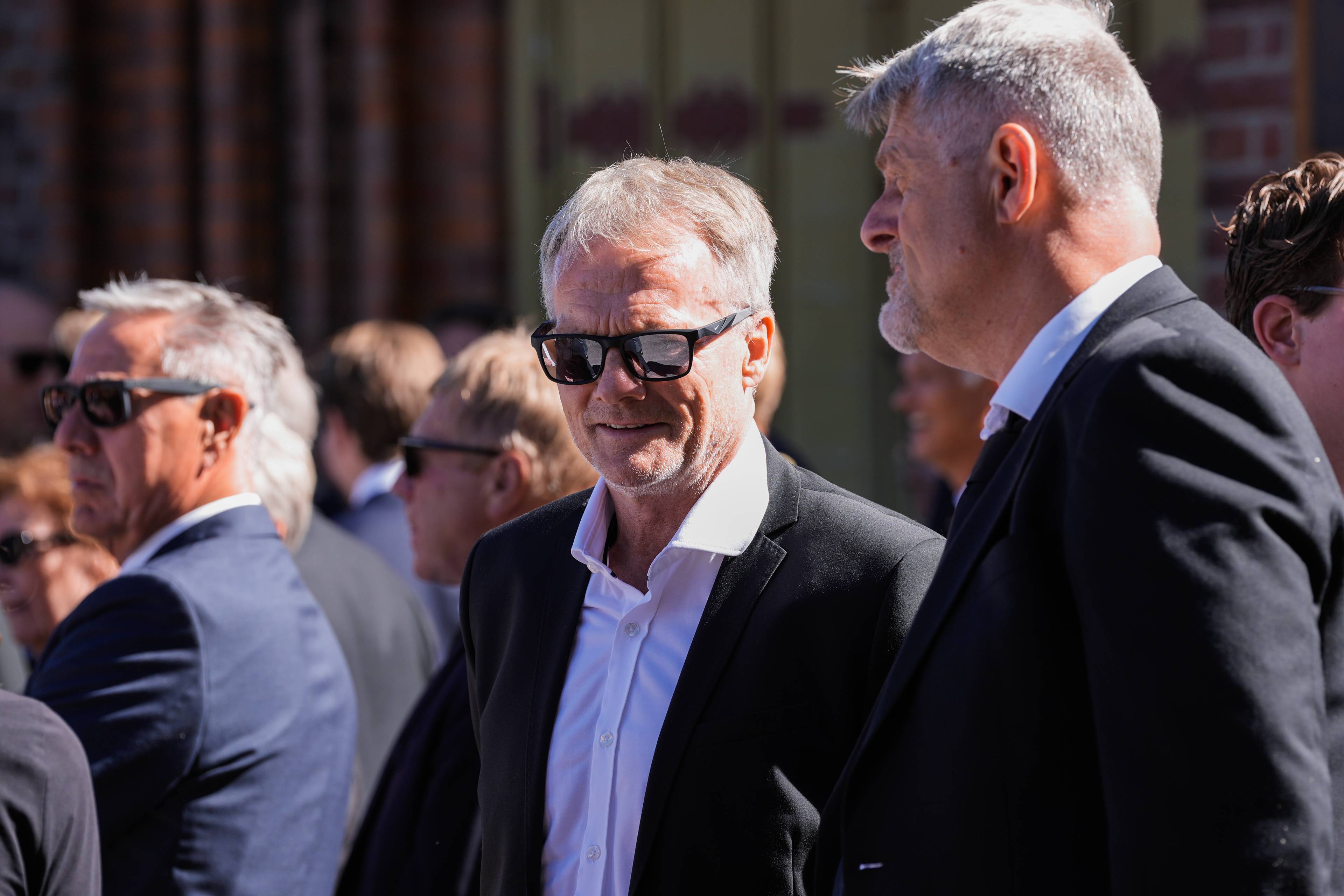 Frode Grodås og andre menn i dress utendørs. Flere bærer solbriller.