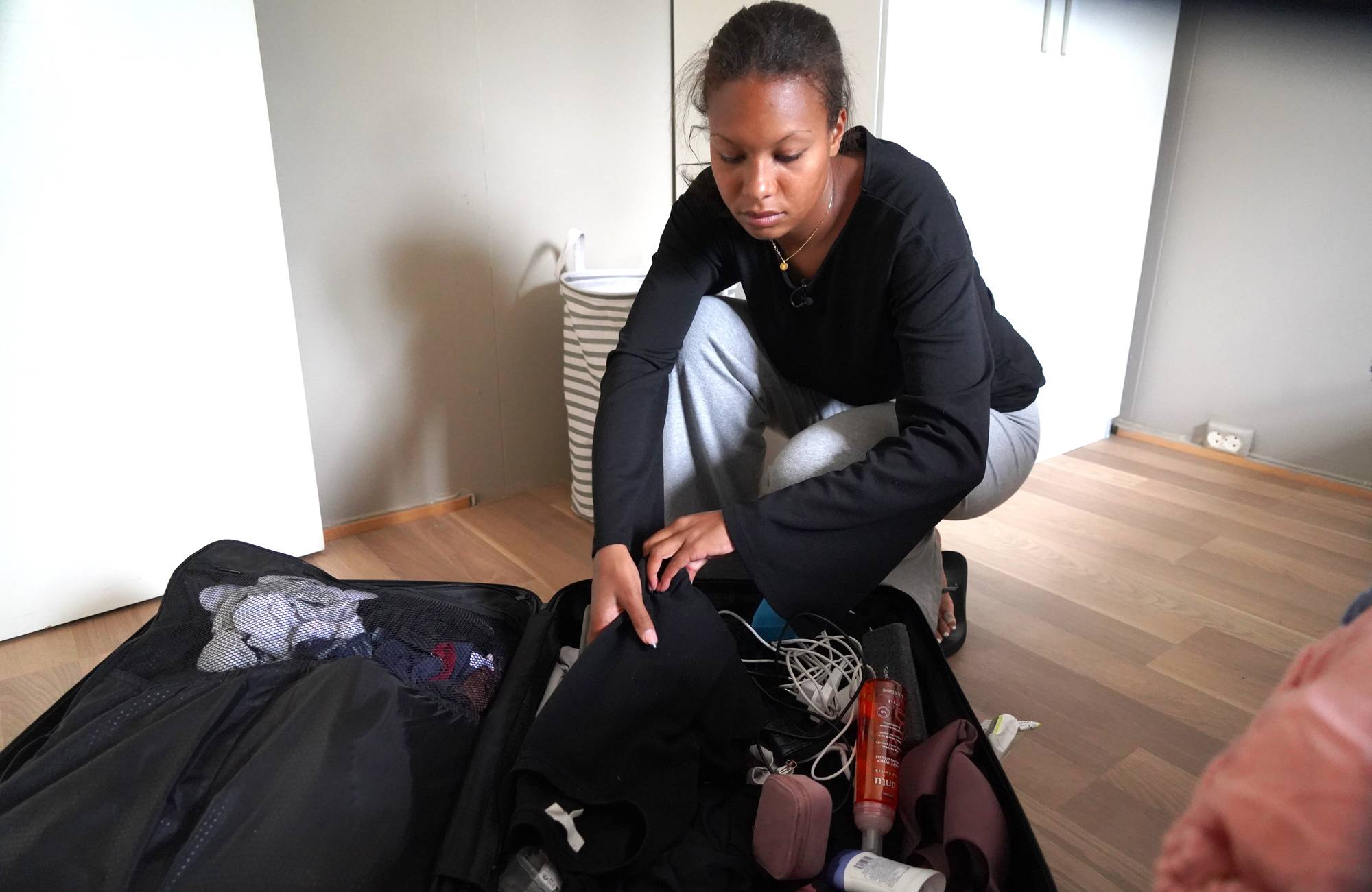 En kvinne pakker ut av en koffert på gulvet. (Bildebeskrivelsen er laget av en KI-tjeneste)