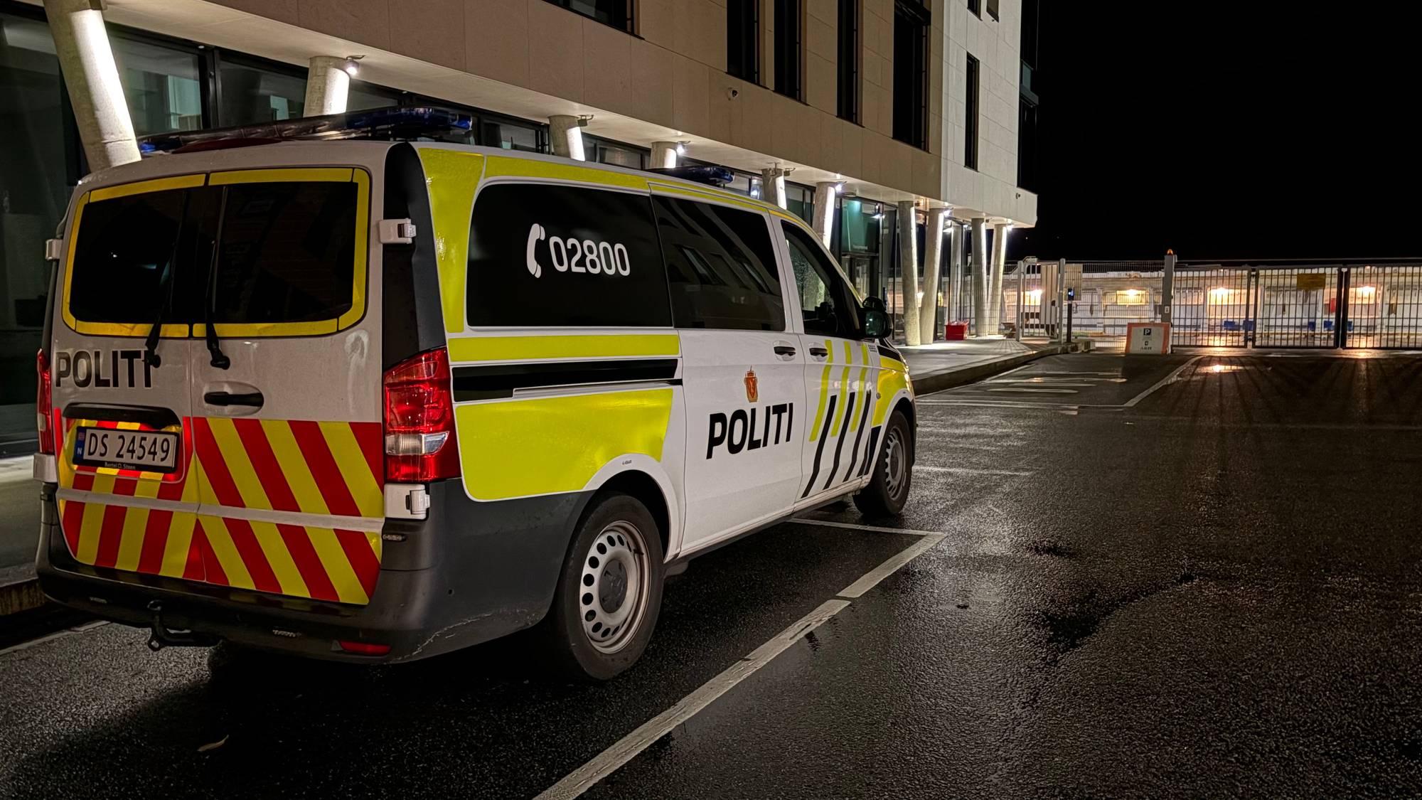 En politibil står parkert utenfor en bygning om natten. (Bildebeskrivelsen er laget av en KI-tjeneste)