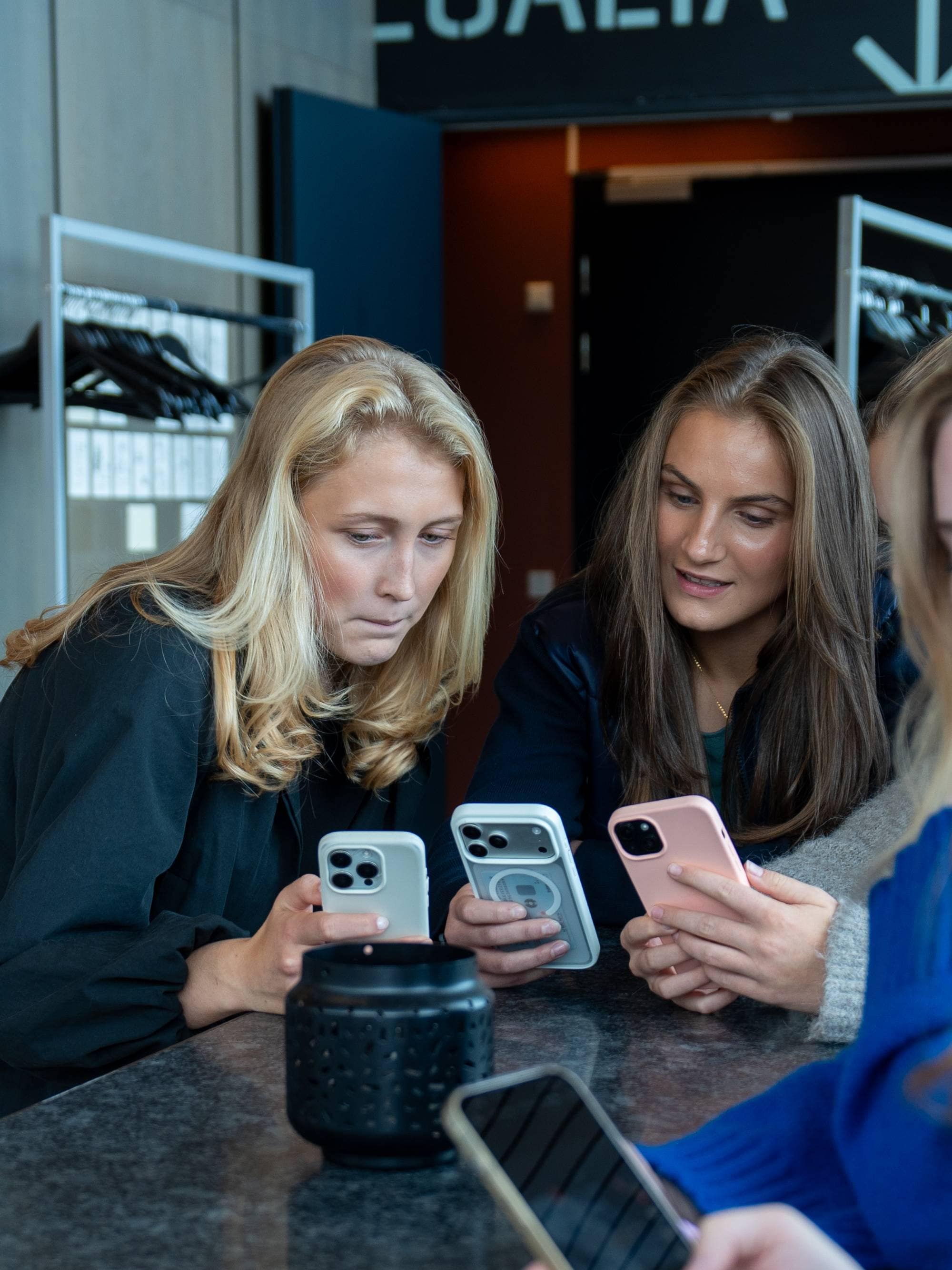 Fem personer sitter rundt et bord og ser ned på hver sin mobiltelefon. (Bildebeskrivelsen er laget av en KI-tjeneste)