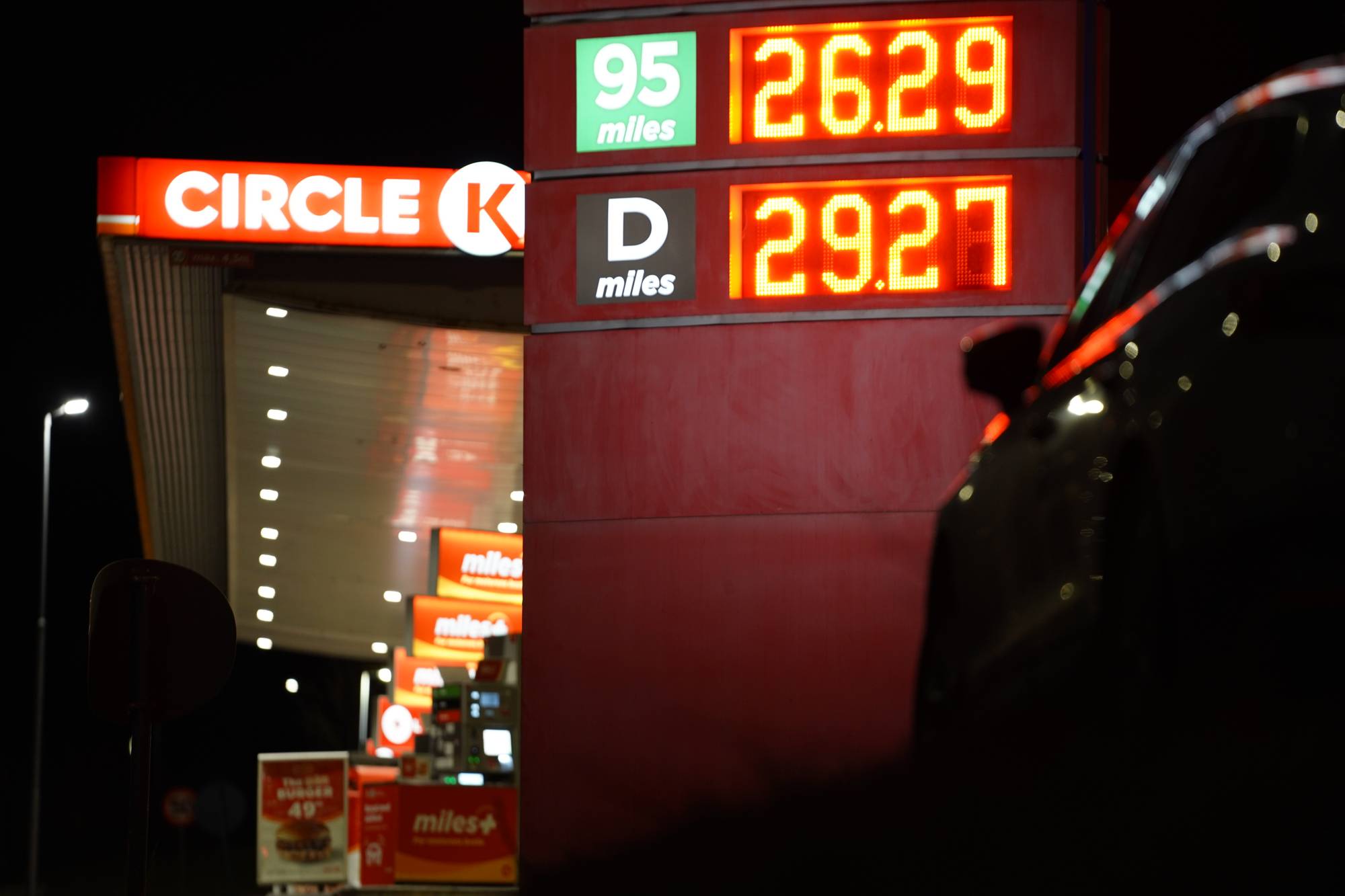 Lysende prisskilt ved bensinstasjon om natten med drivstoffpriser for bensin og diesel. (Bildebeskrivelsen er laget av en KI-tjeneste)