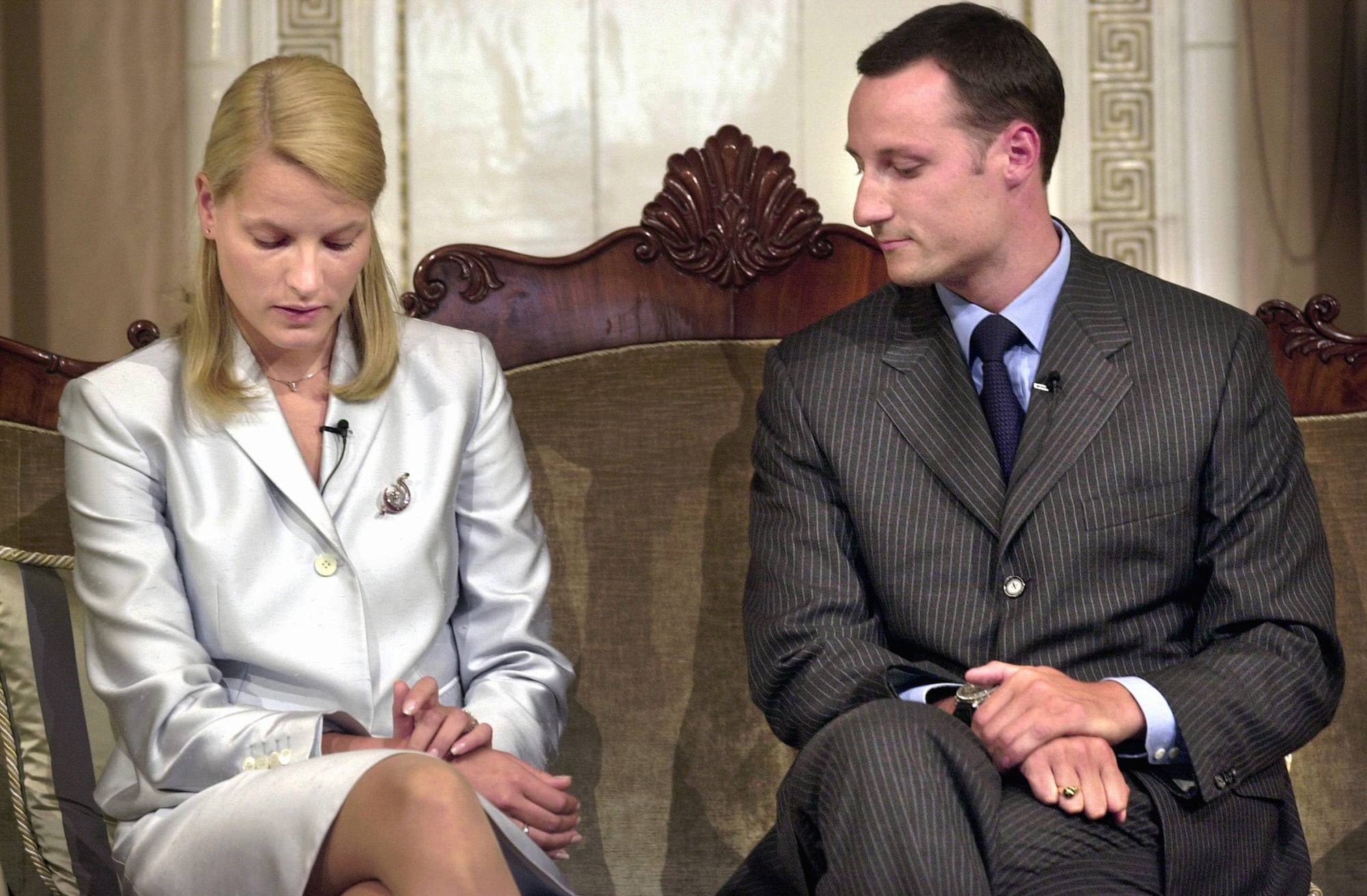 Kronprins Haakon og Mette-Marit Tjessem Høiby sitter i en sofa på Slottet, de ser ned mot en lapp Mette-Marit holder.