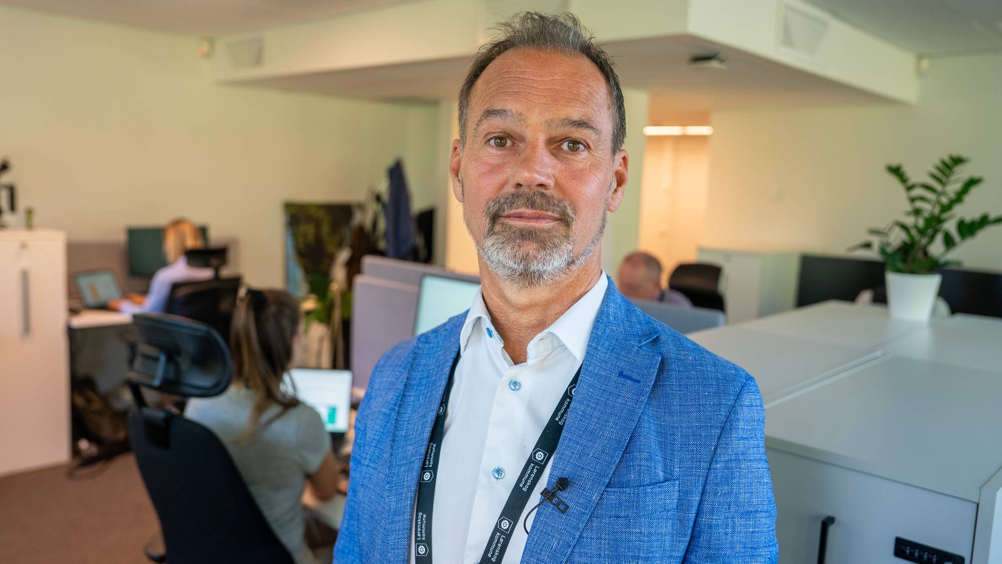 Mann i blå blazer i et kontorlandskap