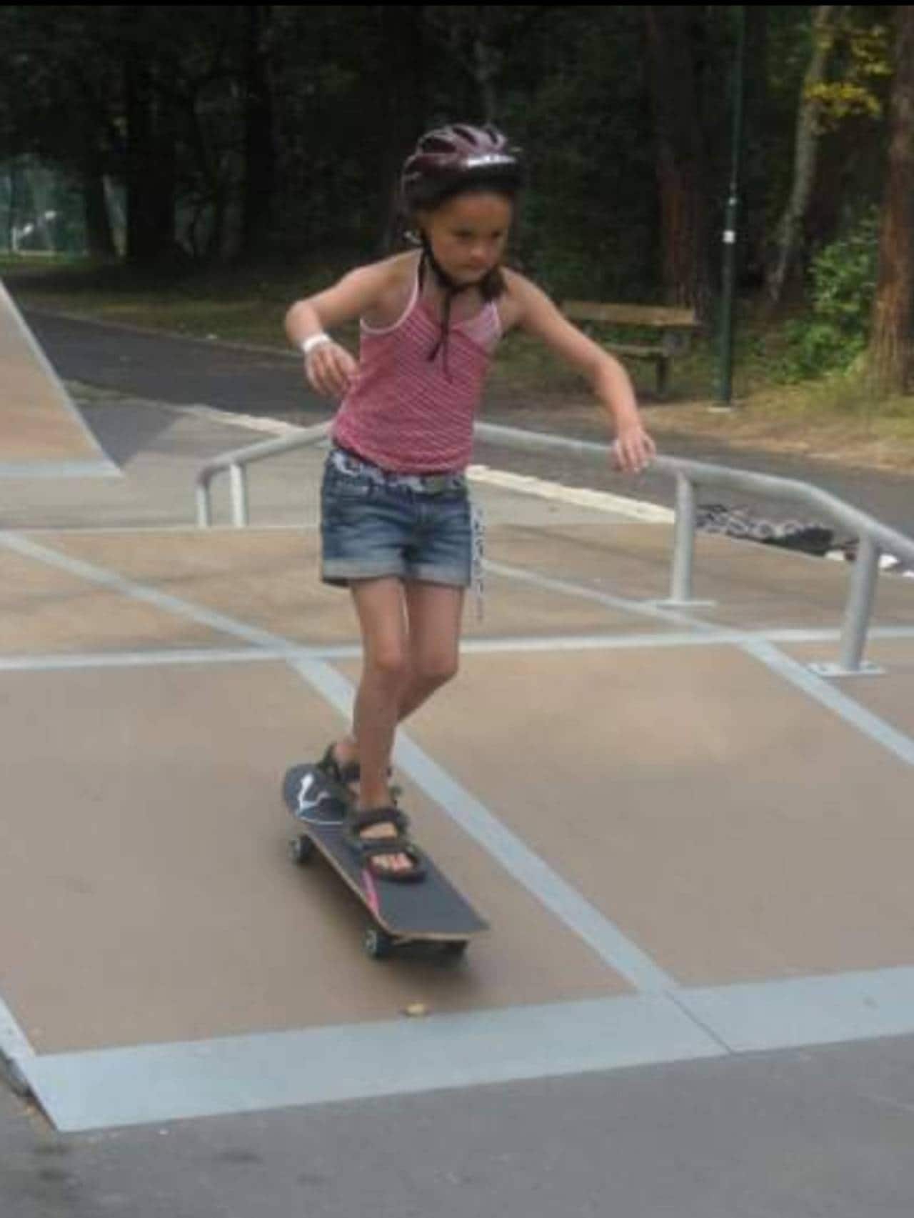Andrine står på skateboard.