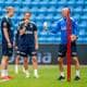 Fredrik Varfjell / NTB Trenere og spillere på en fotballbane. En trener holder et papir og en fotball, mens flere spillere står rundt ham. Bak dem ser man tomme tribuner. (Bildebeskrivelsen er laget av en KI-tjeneste)