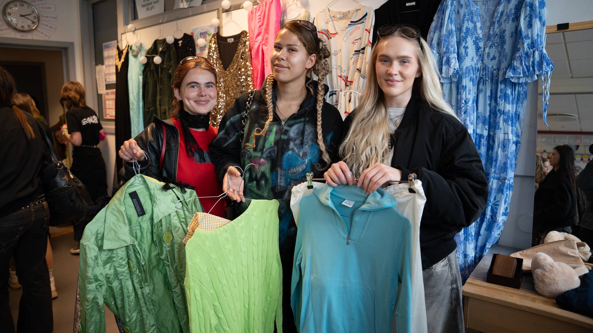 Tre unge jenter står og poserer med grønne skjorter de har funnet på loppemarked