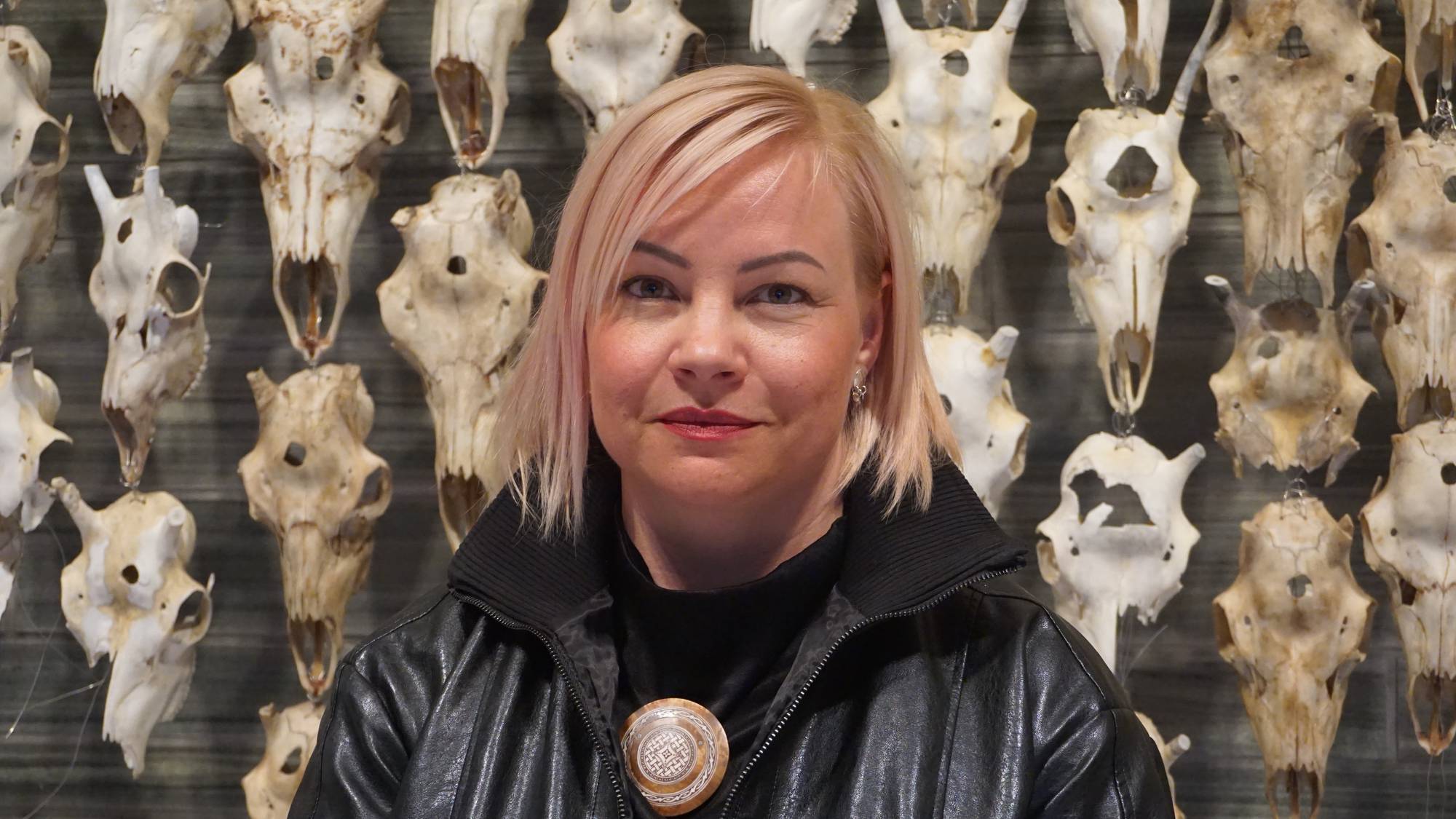 Máret Ánne Sara čuožžu ovddabeal su «Pile o’Sápmi Supreme» dáidaga. / Máret Ánne Sara. Kunstverket «Pile o’Sápmi Supreme» henger på veggen bak henne. 