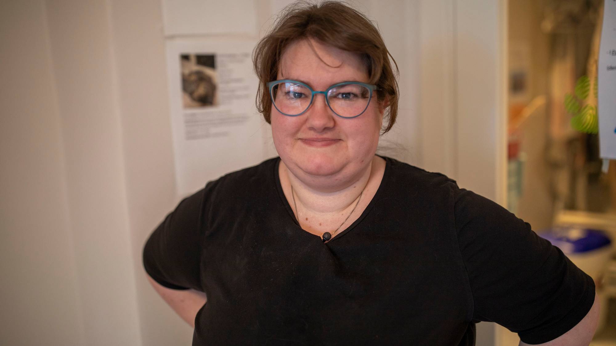 Gunhild Heni Peterzens har på seg svart t-skjorte og briller. Hun ser inn i kameraet og smiler