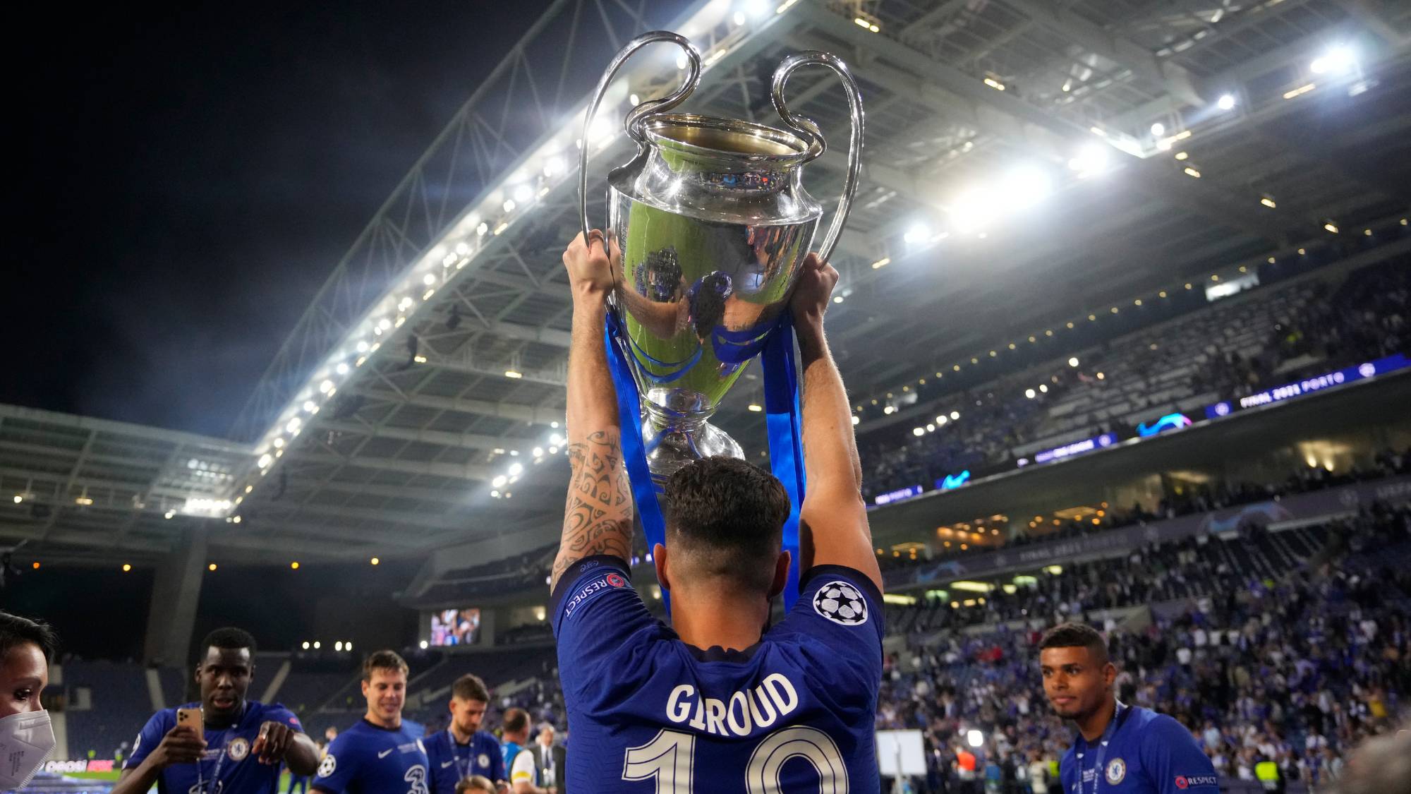 Olivier Giroud holder Mesterliga-trofeet over hodet, vendt bort mot kamera, og jubler mot publikum