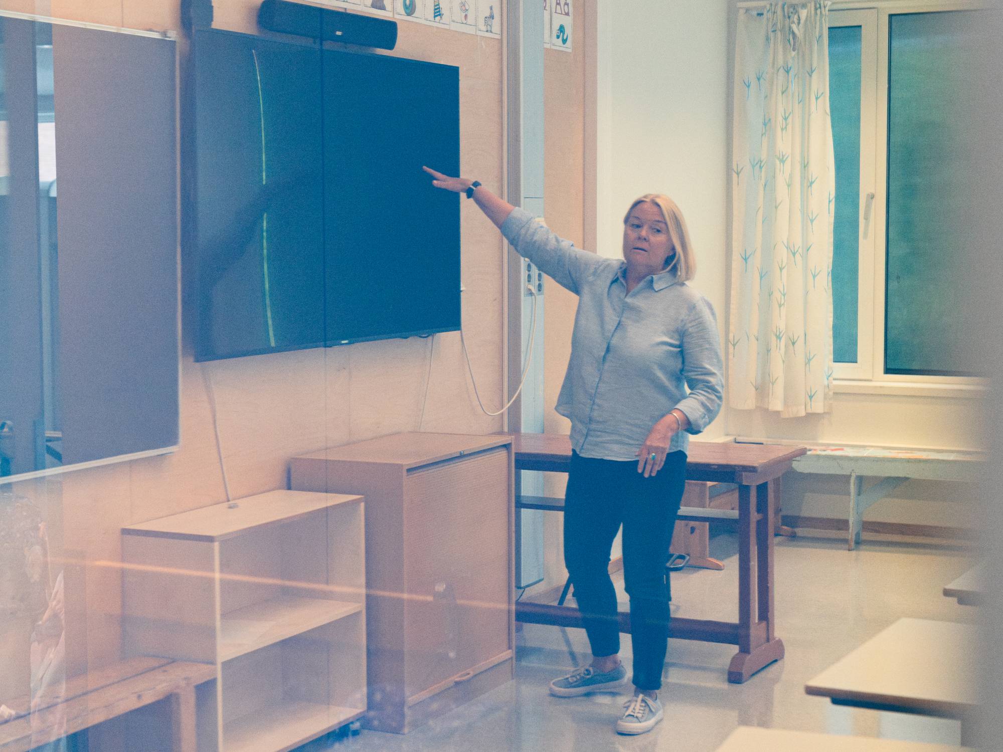 Kvinne peker på en skjerm i et klasserom.