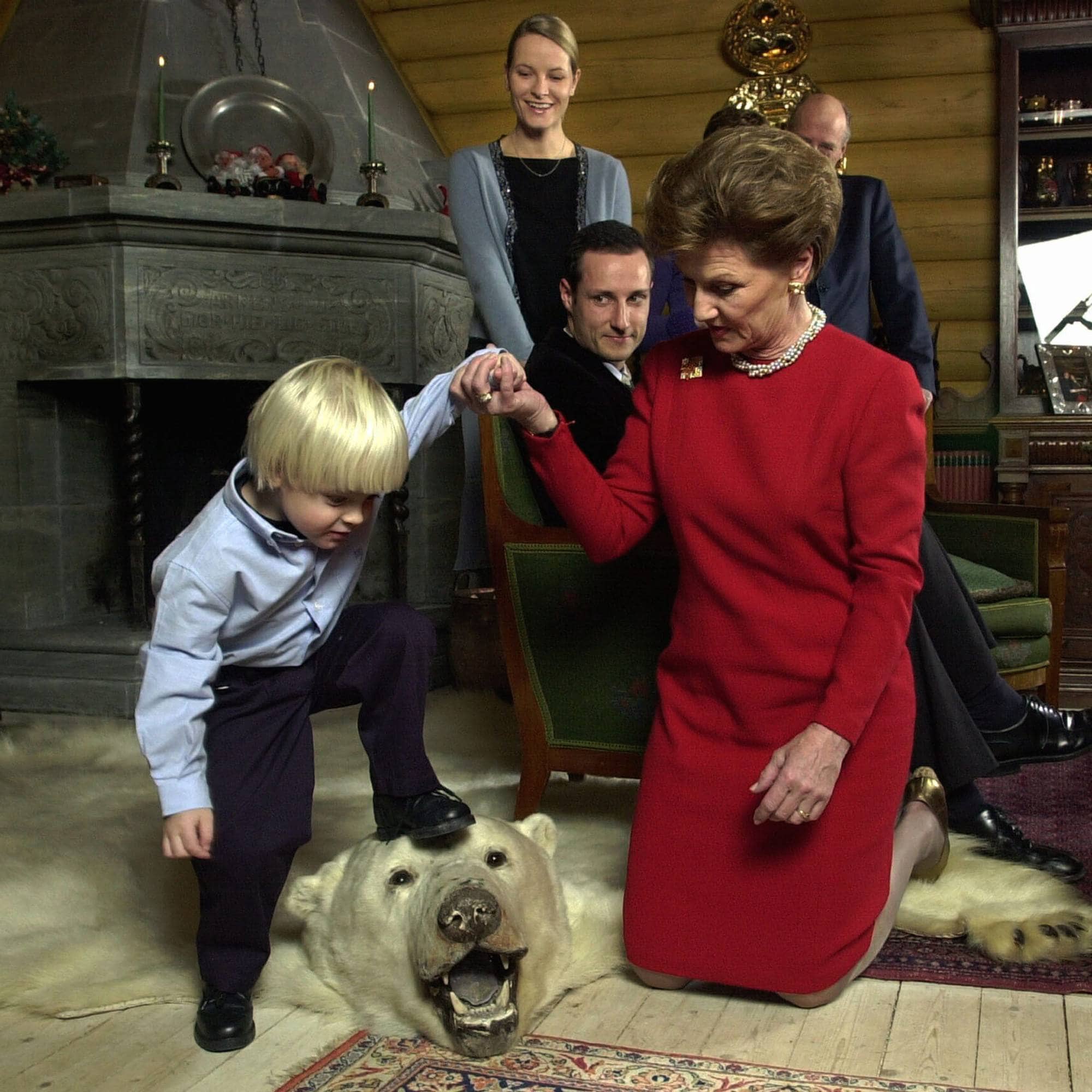Kongeparet og kronprinsparet og Marius Borg Høiby på julefotografering, Marius klatrer på et isbjørnskinn, mens dronning Sonja holder ham i hånden
