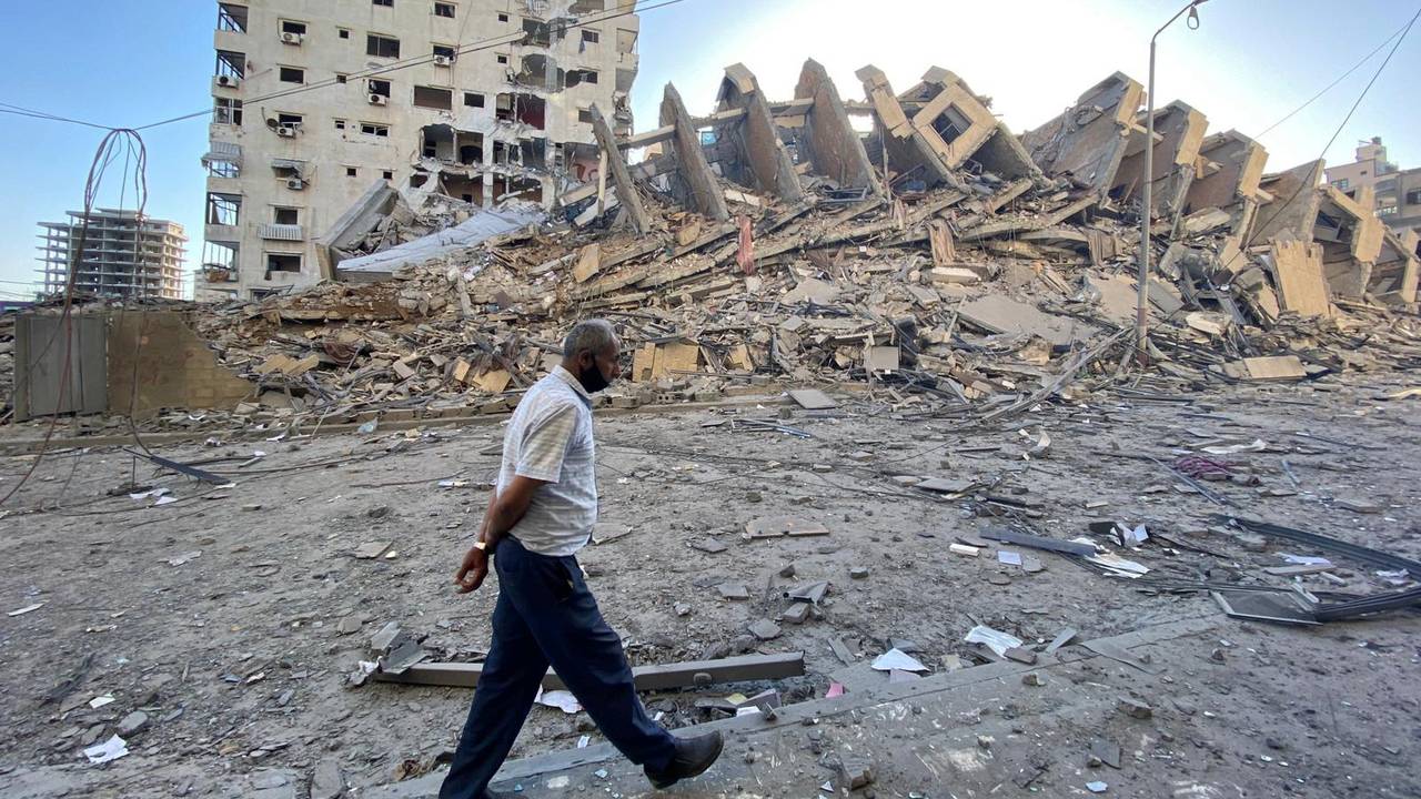 Mann går 12. mai forbi en boligblokk som ble ødelagt i Gaza by, etter israelske flyangrep.