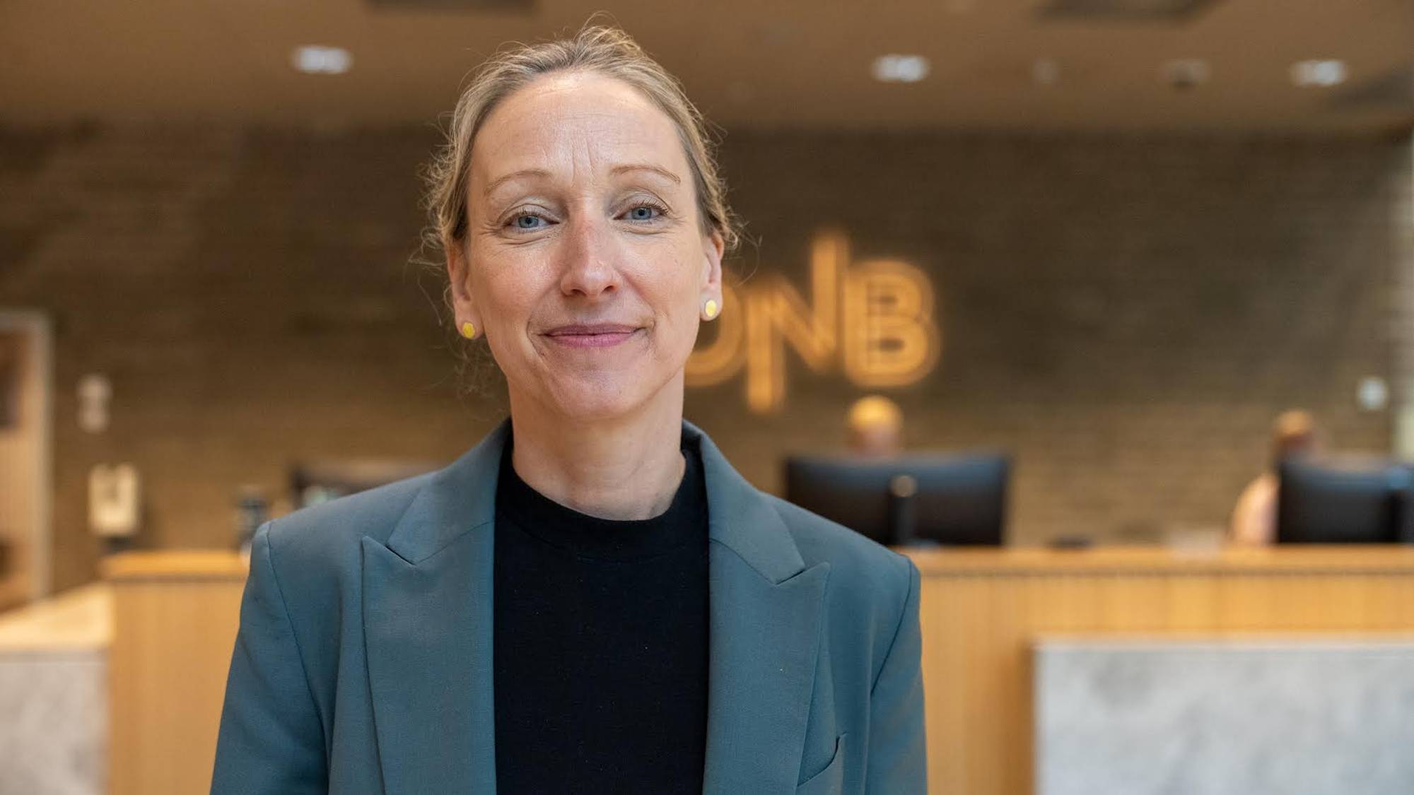 Kvinne i grå blazer og svart overdel står føre DNB-resepsjonen. 