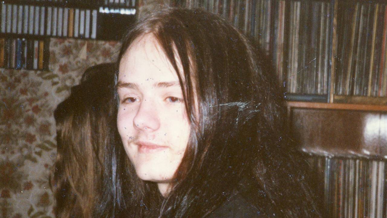 Øystein Aarseth som tenåring foran en hylle med vinylplater, med langt svart hår.