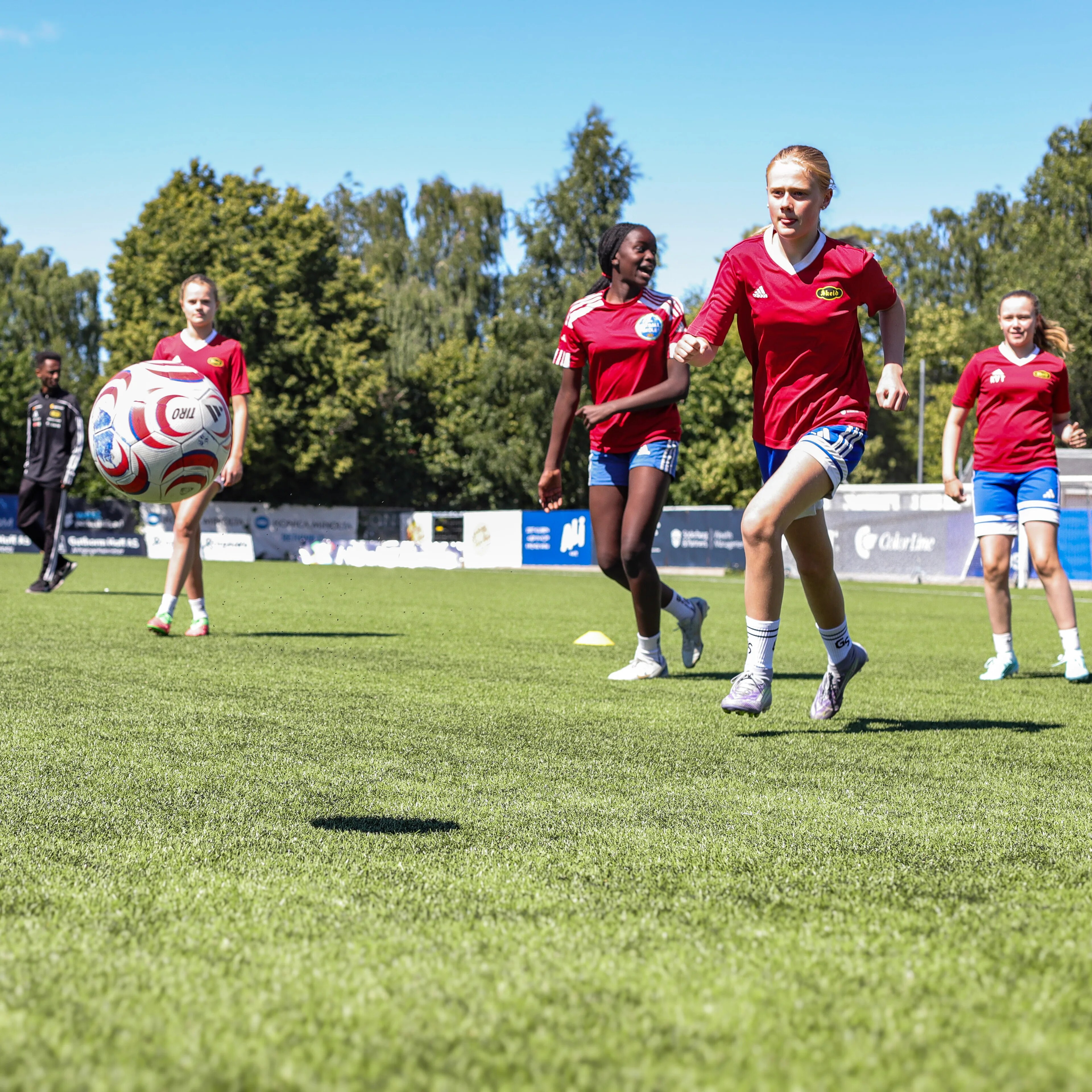 Flere jenter som løper etter en ball på en fotballbane.