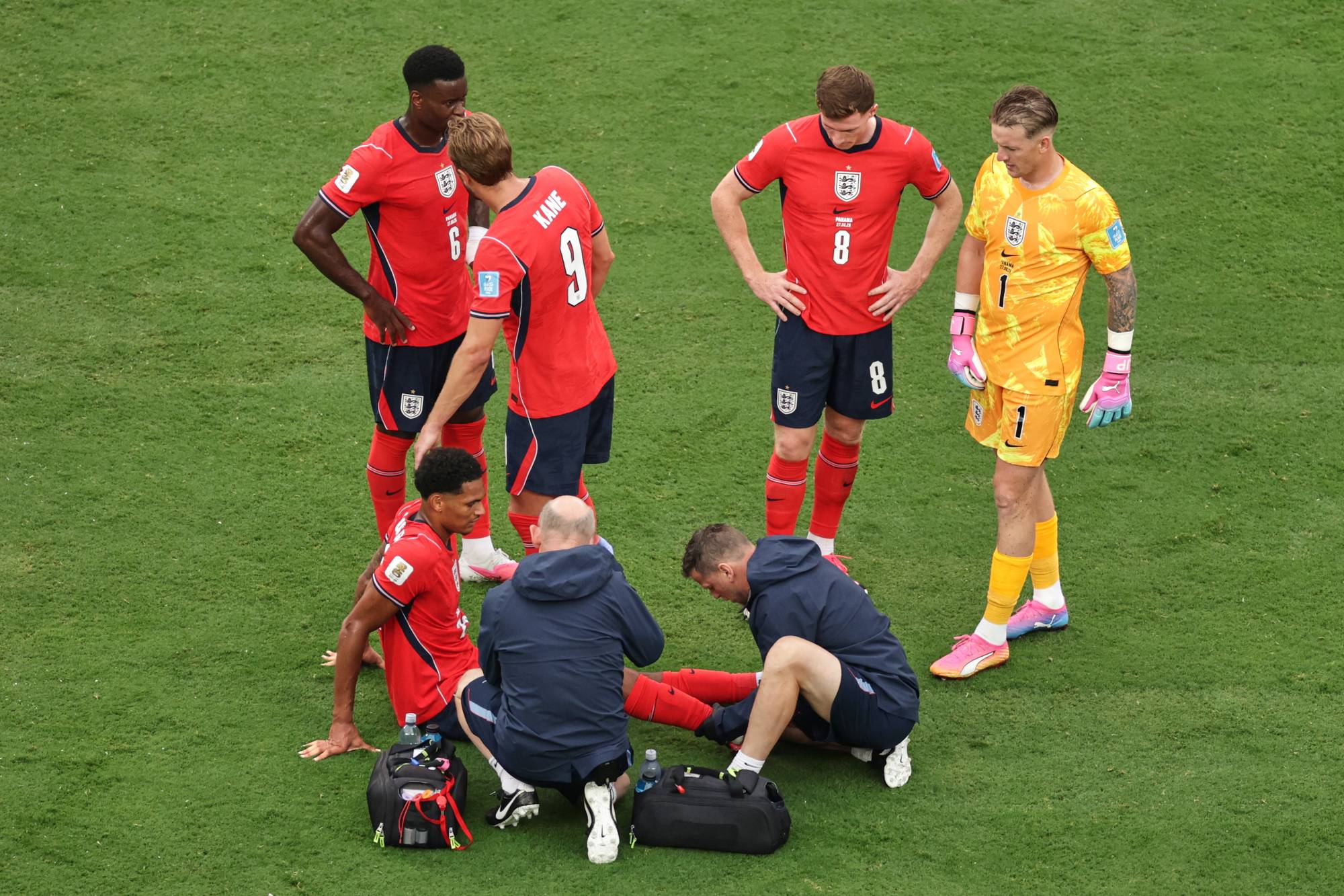 Medisinske apparater behandler en skadet fotballspiller fra England på gressbanen. (Bildebeskrivelsen er laget av en KI-tjeneste)