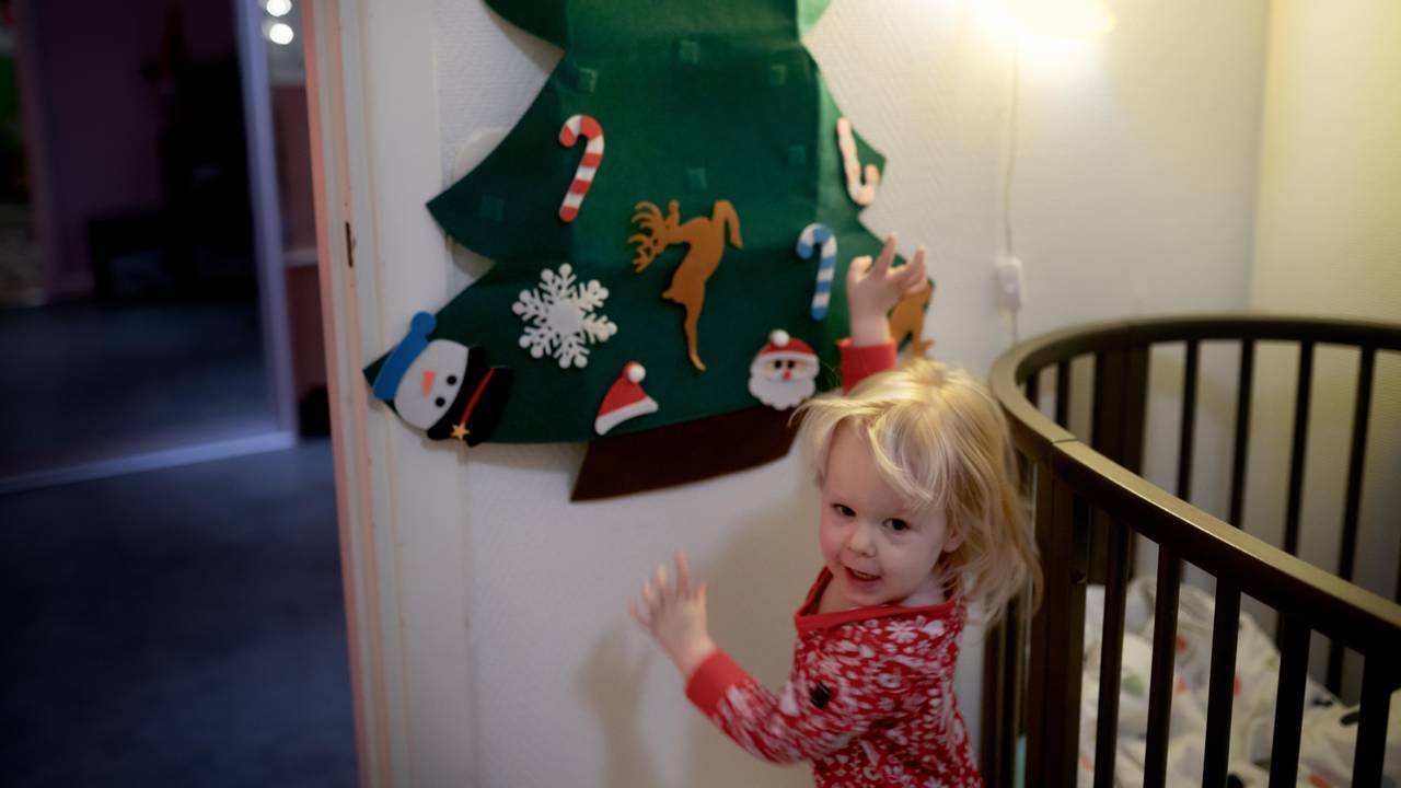 Nanna Trollnes (2) henger julepynt på filt-juletreet på rommet sitt.