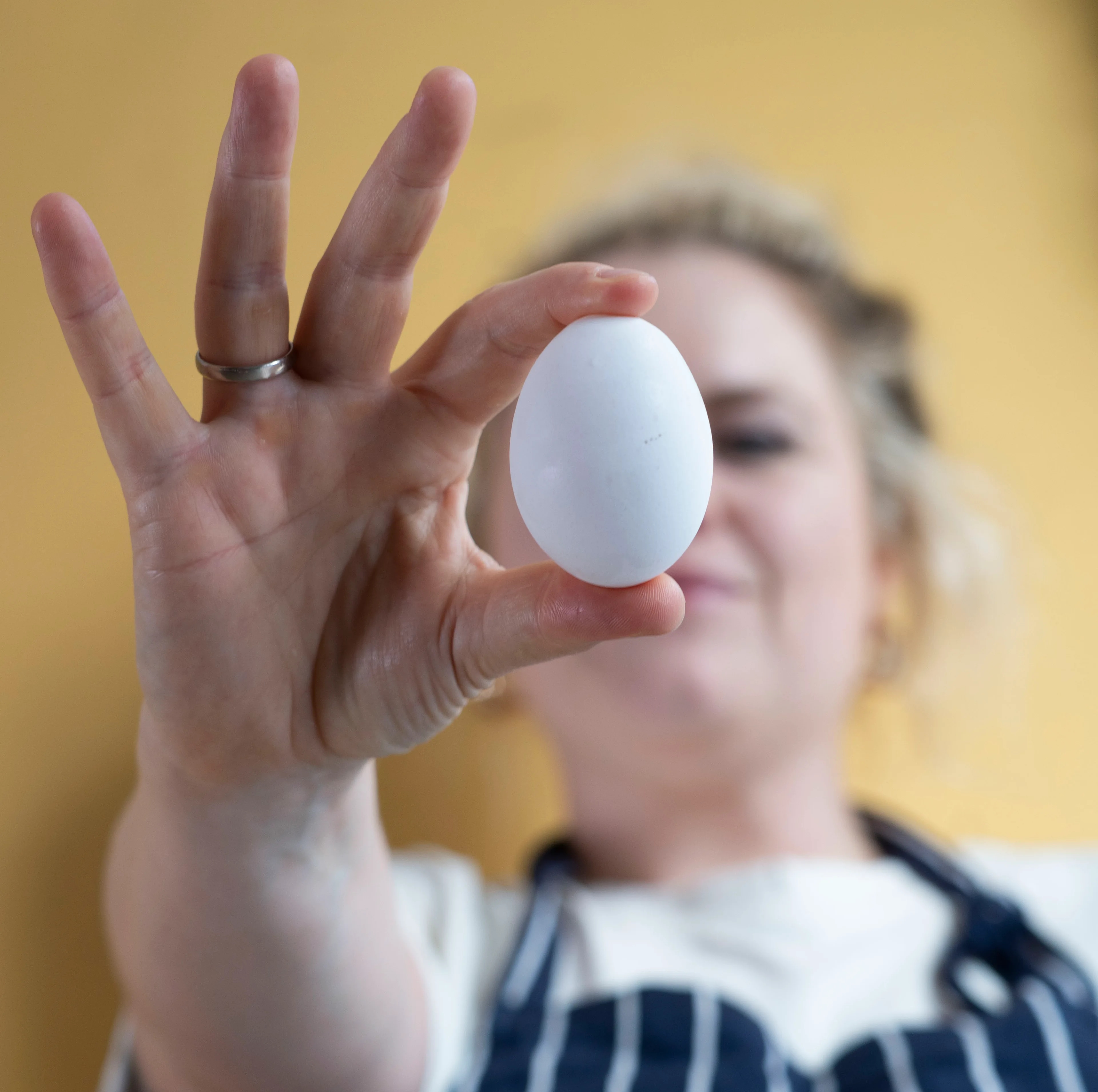 En kvinner holder et egg opp mot kamera