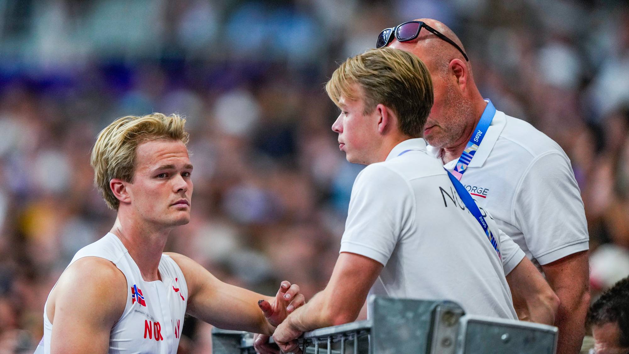 Sondre Guttormsen (t.v.) sammen med bror Simen og trener og far Atle Guttormsen under finale i stav på Stade de France under sommer OL i Paris 2024.