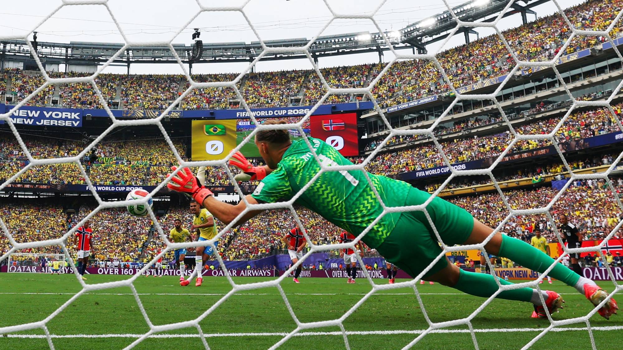 Keeper i grønn drakt kaster seg for å redde en fotball foran et stappfullt stadion. Illustrasjon. (Bildebeskrivelsen er laget av en KI-tjeneste)